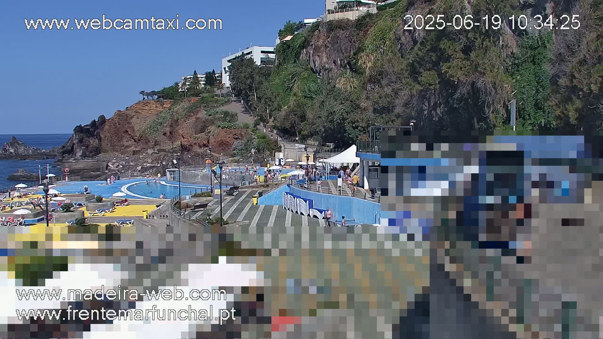 An outdoor oceanside pool complex with many people enjoying a sunny day.