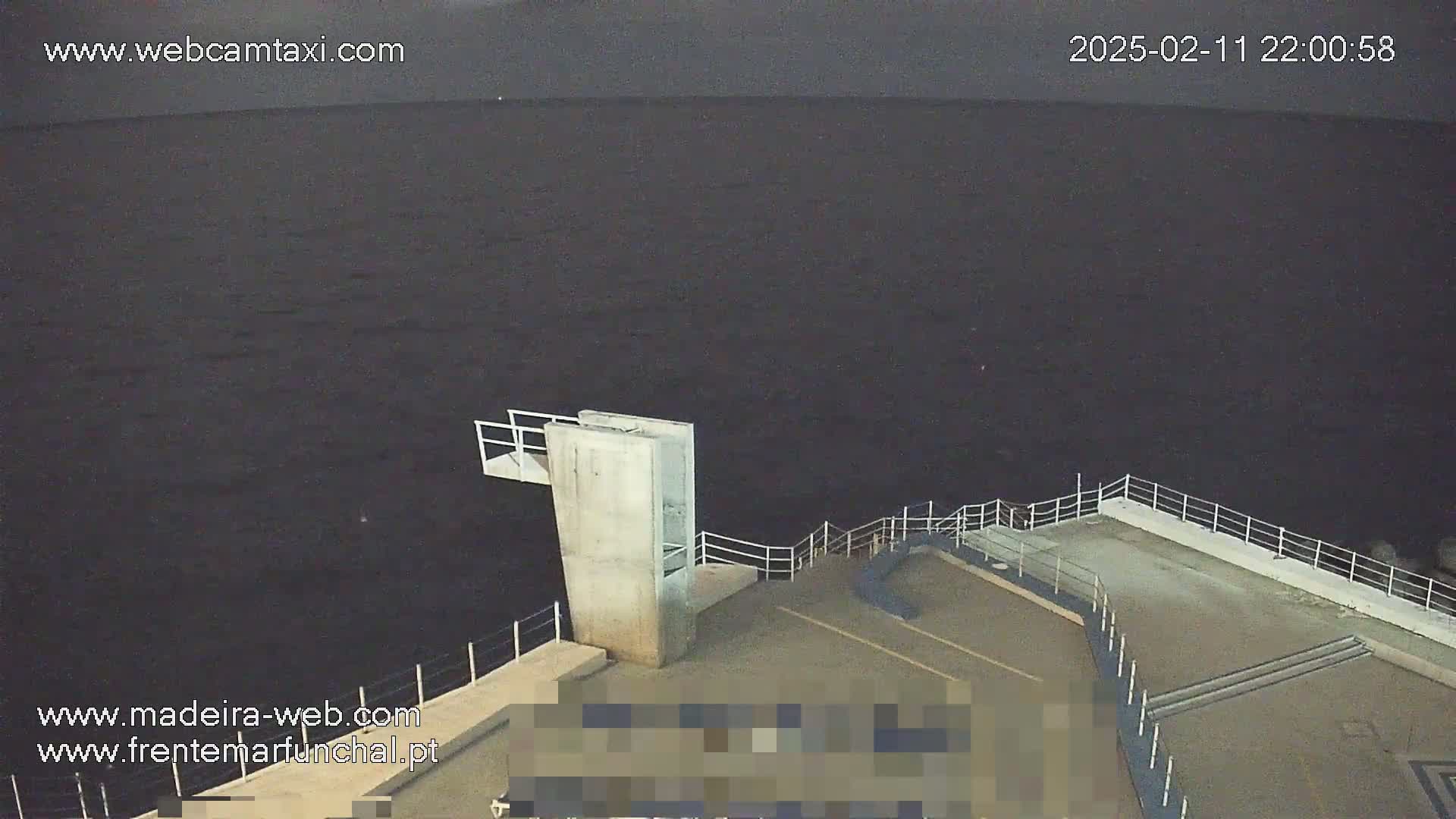 A nighttime view of a concrete structure with railings overlooking dark water.