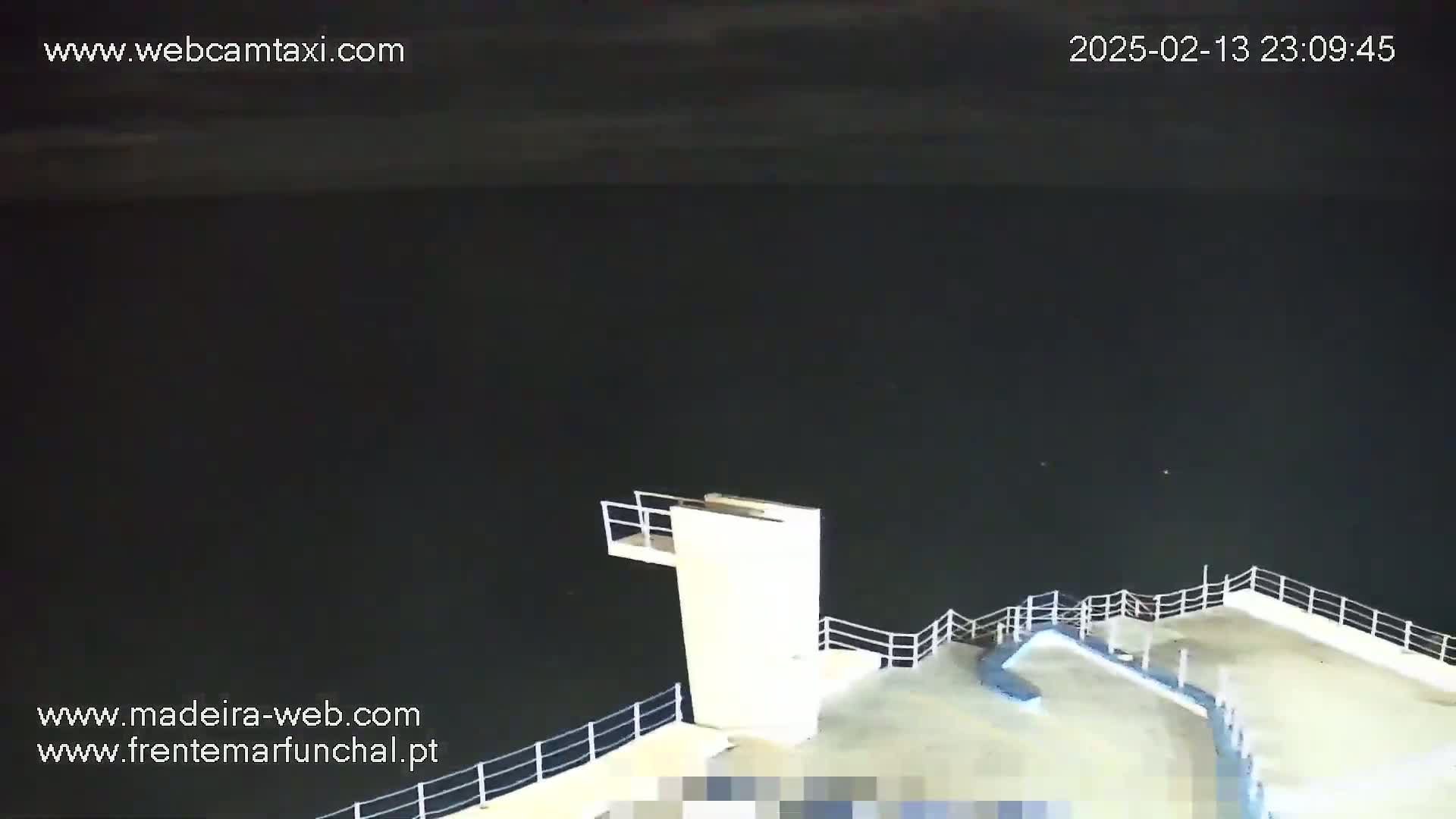 A nighttime view of a diving platform on a pier overlooking dark water.