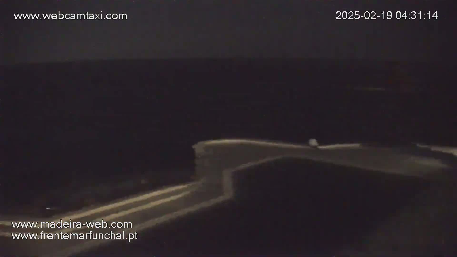 A nighttime, low-light view shows a section of a road curving gently to the right.