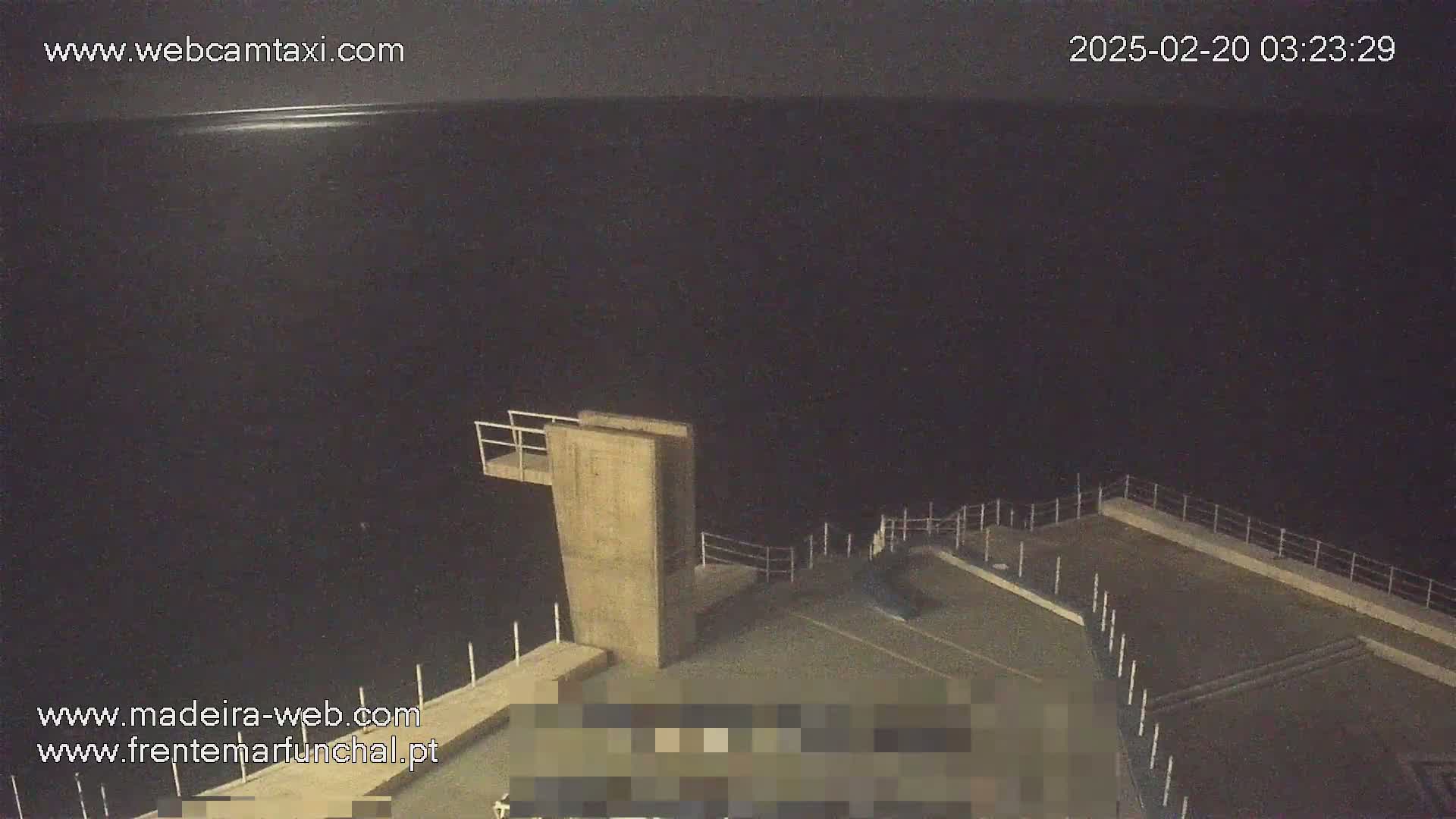 A nighttime view of a high diving platform overlooking a dark body of water.