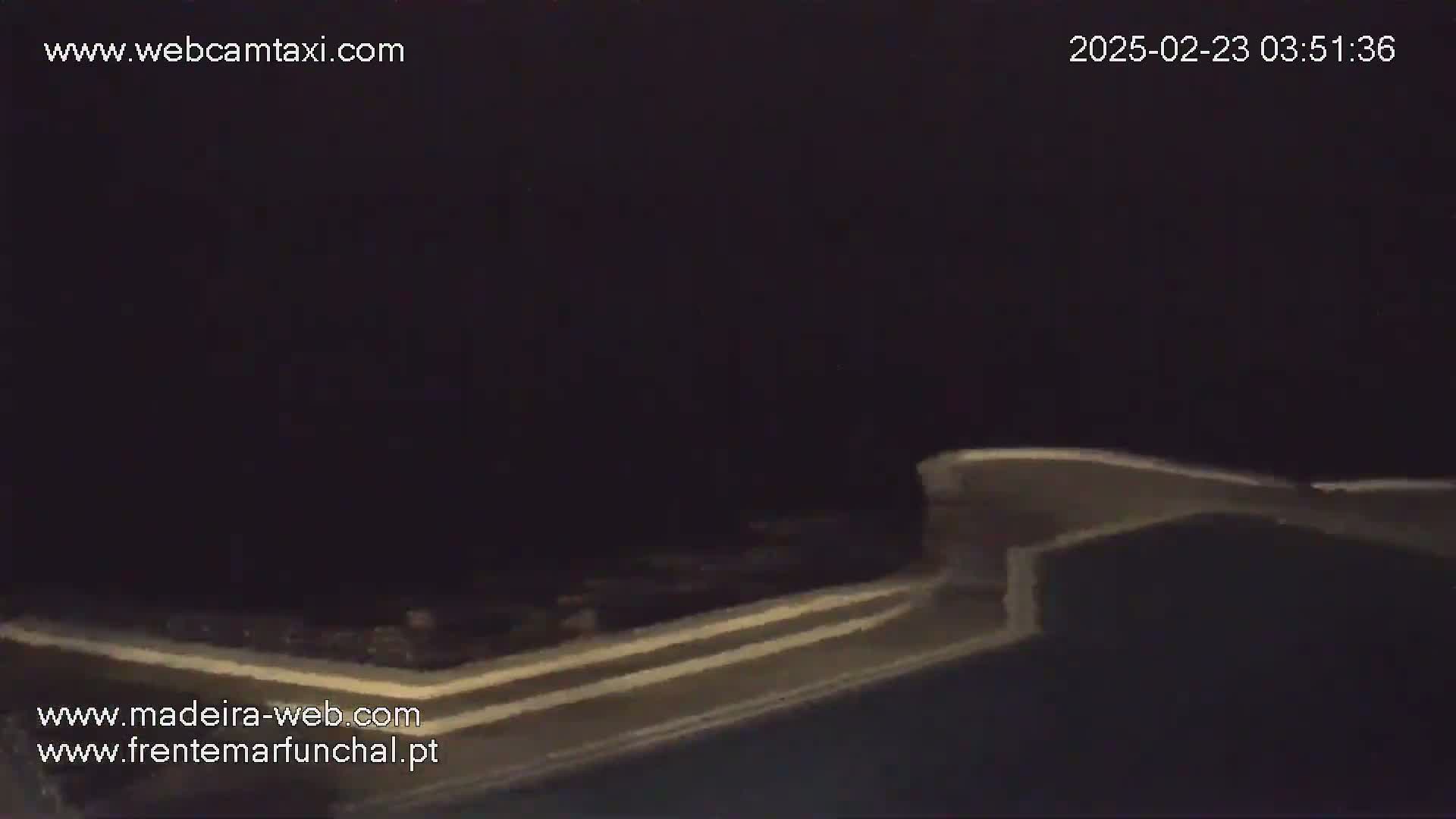 A dimly lit, nighttime scene shows a portion of a structure, possibly a wall or a roadway, extending across the bottom of the frame.