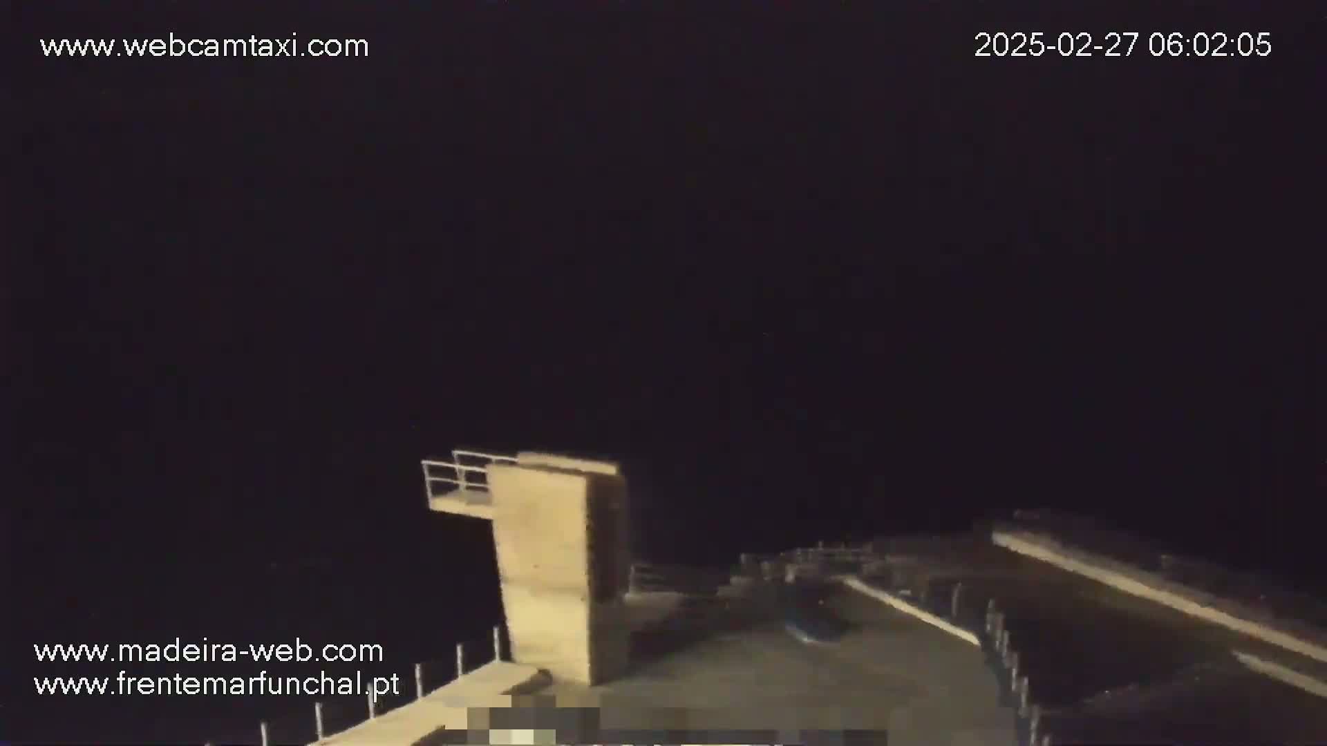 A nighttime view of a diving platform and surrounding area under a dark sky.