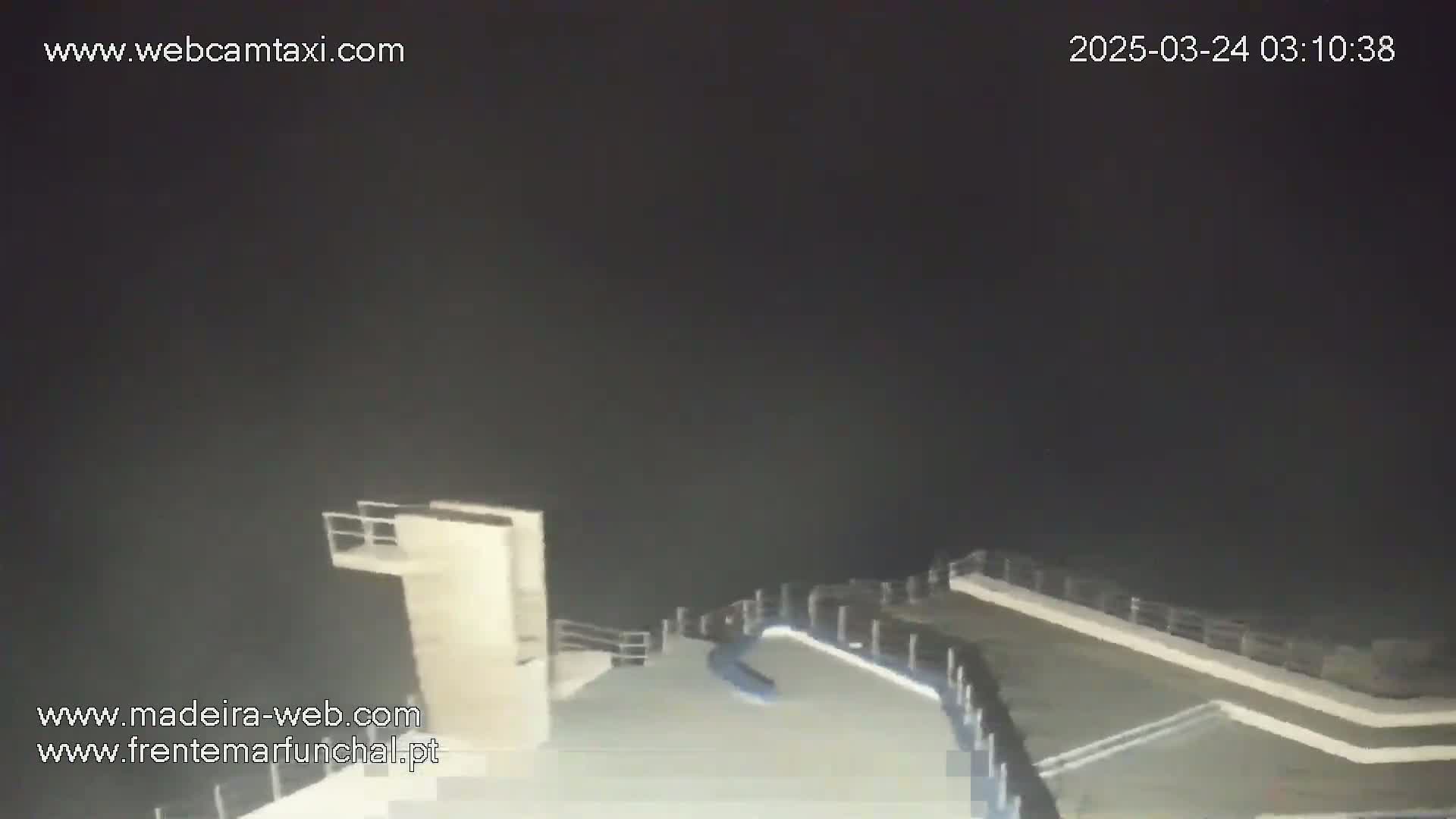 A nighttime view of an empty diving platform and surrounding area under a dark sky.