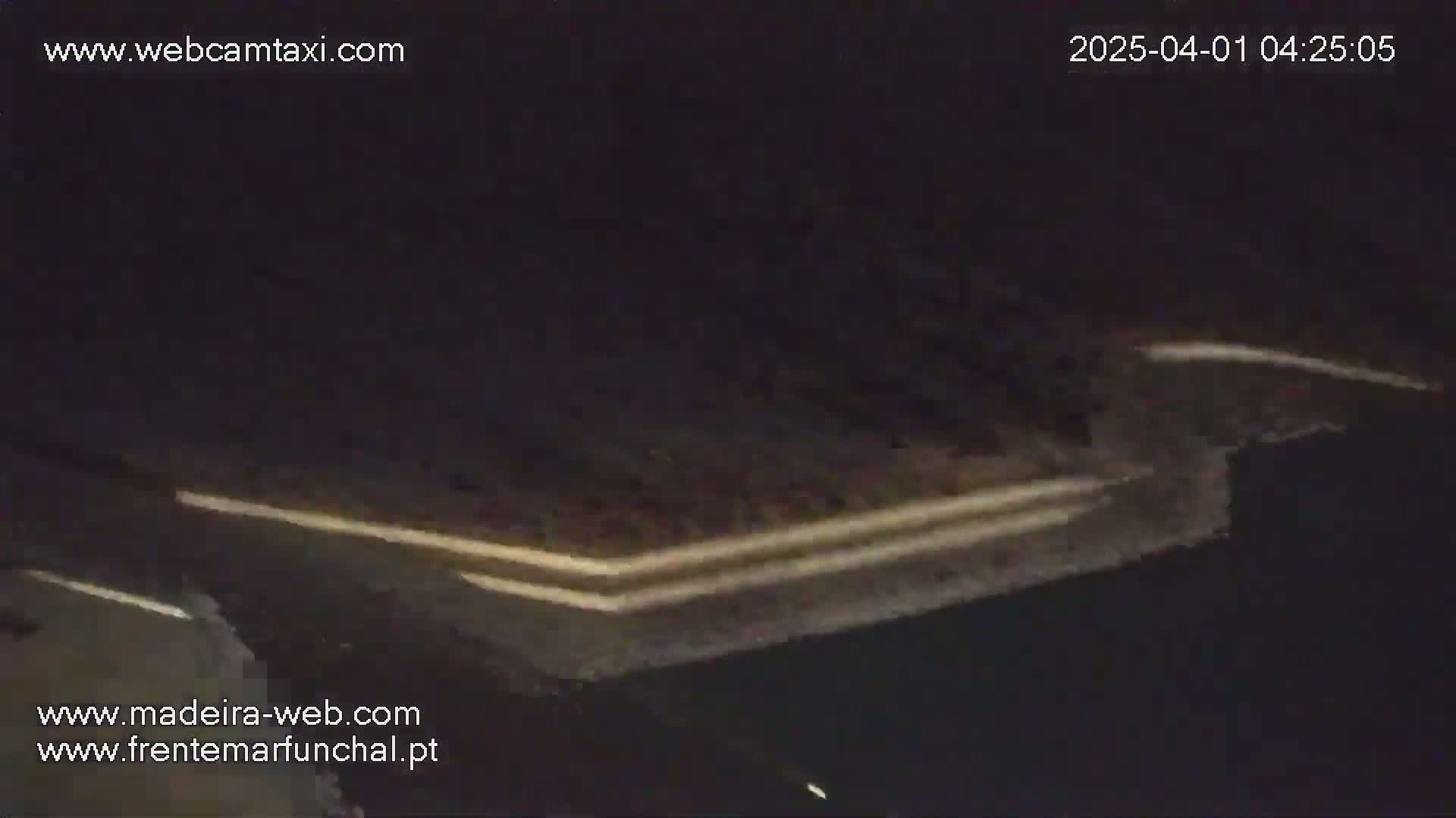 A dark, nighttime image shows a highway with two lanes of traffic visible, illuminated by headlights.