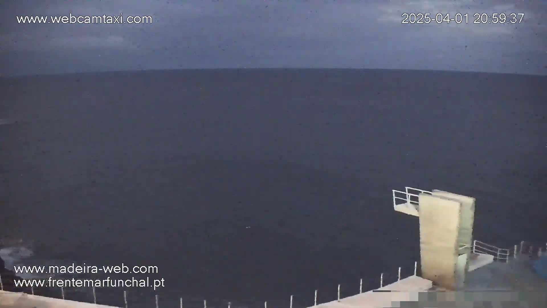 A diving platform overlooks a dark, overcast ocean at night.