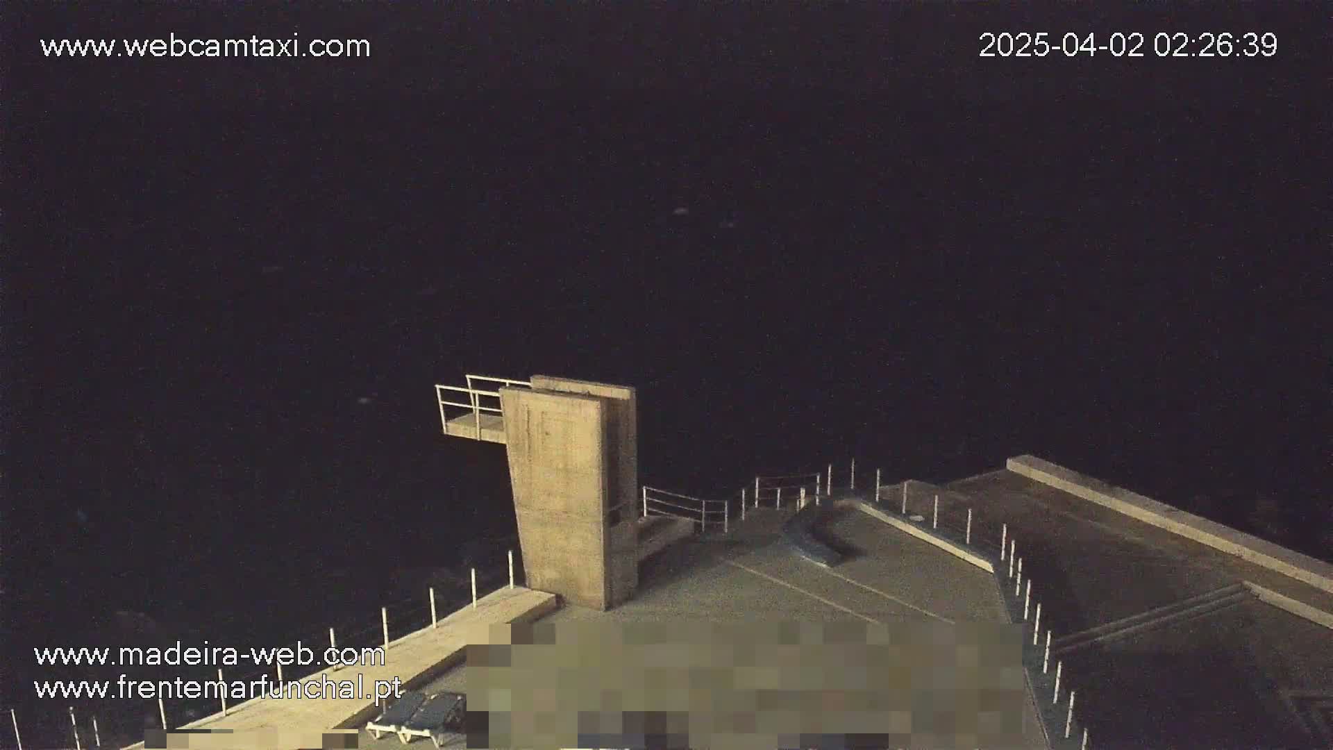 A high-angle nighttime view of a concrete diving platform and surrounding area under a clear, dark sky.