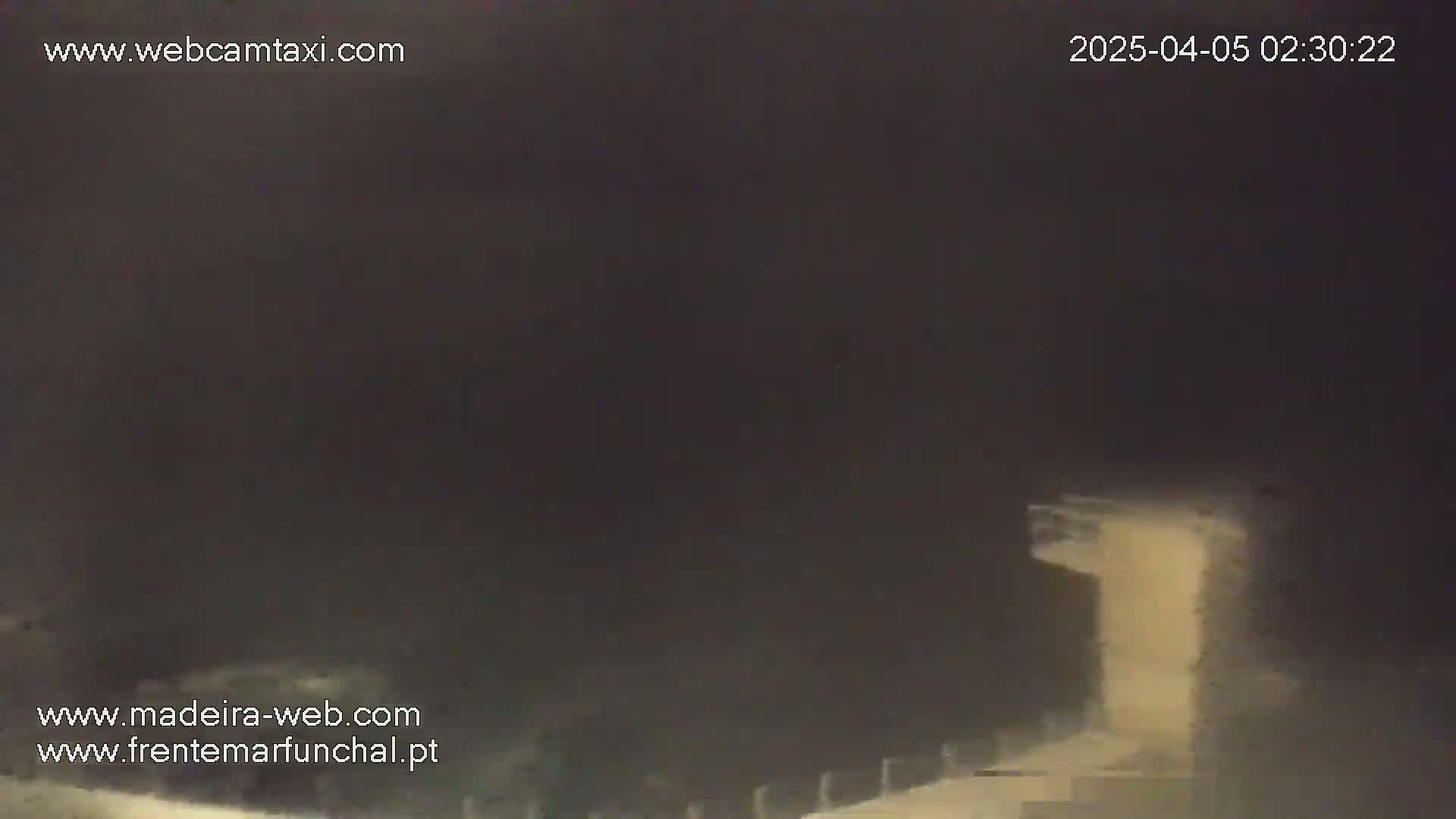 A nighttime, hazy view shows a dimly lit structure with a ramp or path leading up to it.