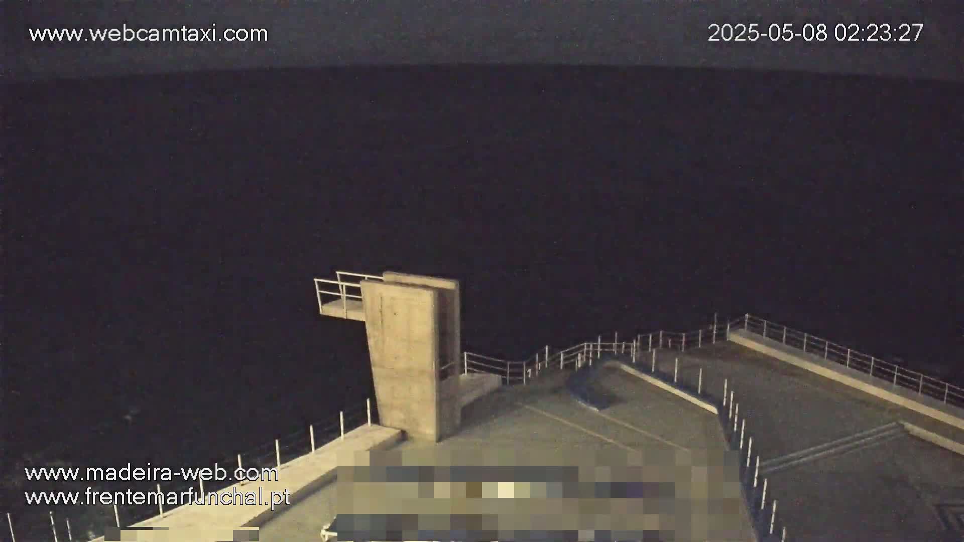 A nighttime view of a concrete diving platform overlooking a dark body of water.