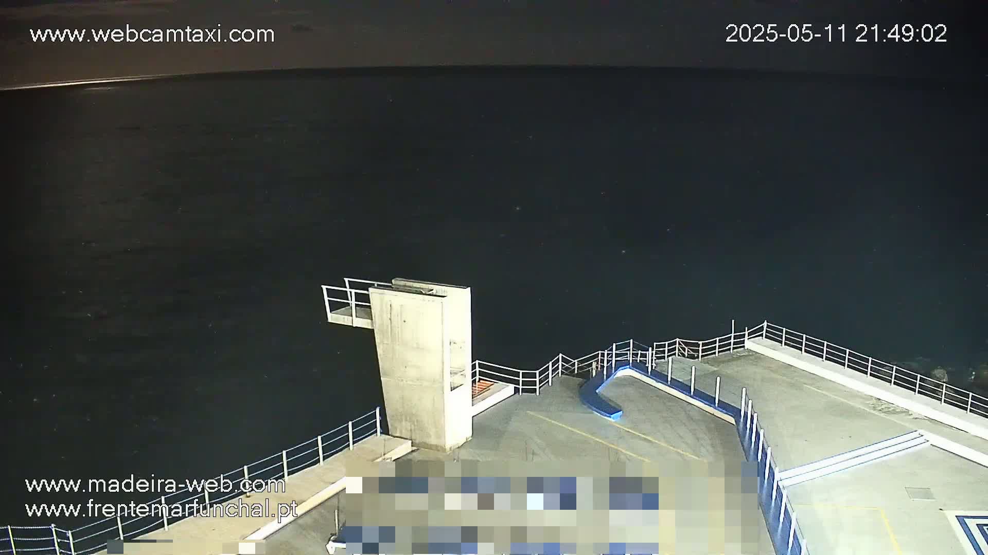 A nighttime view of a concrete diving platform overlooking dark water.