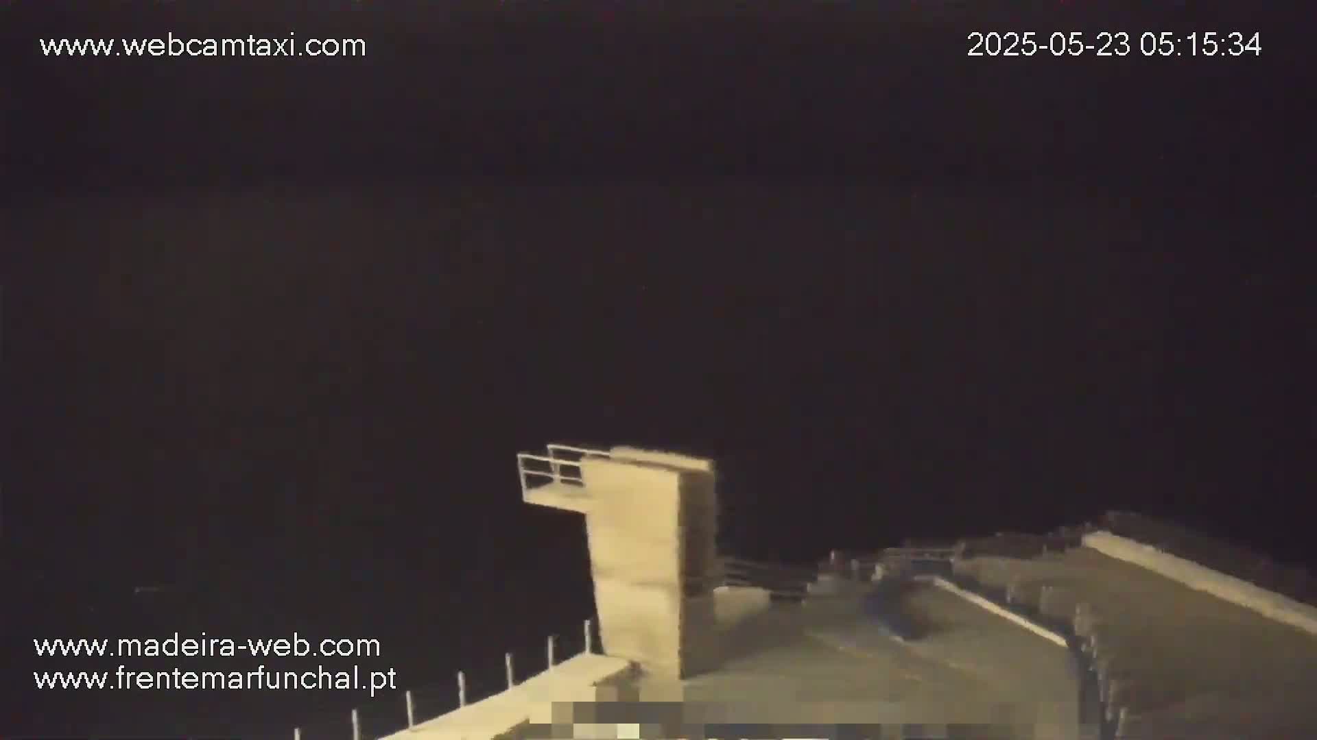 A nighttime view of a low diving platform overlooking dark water.