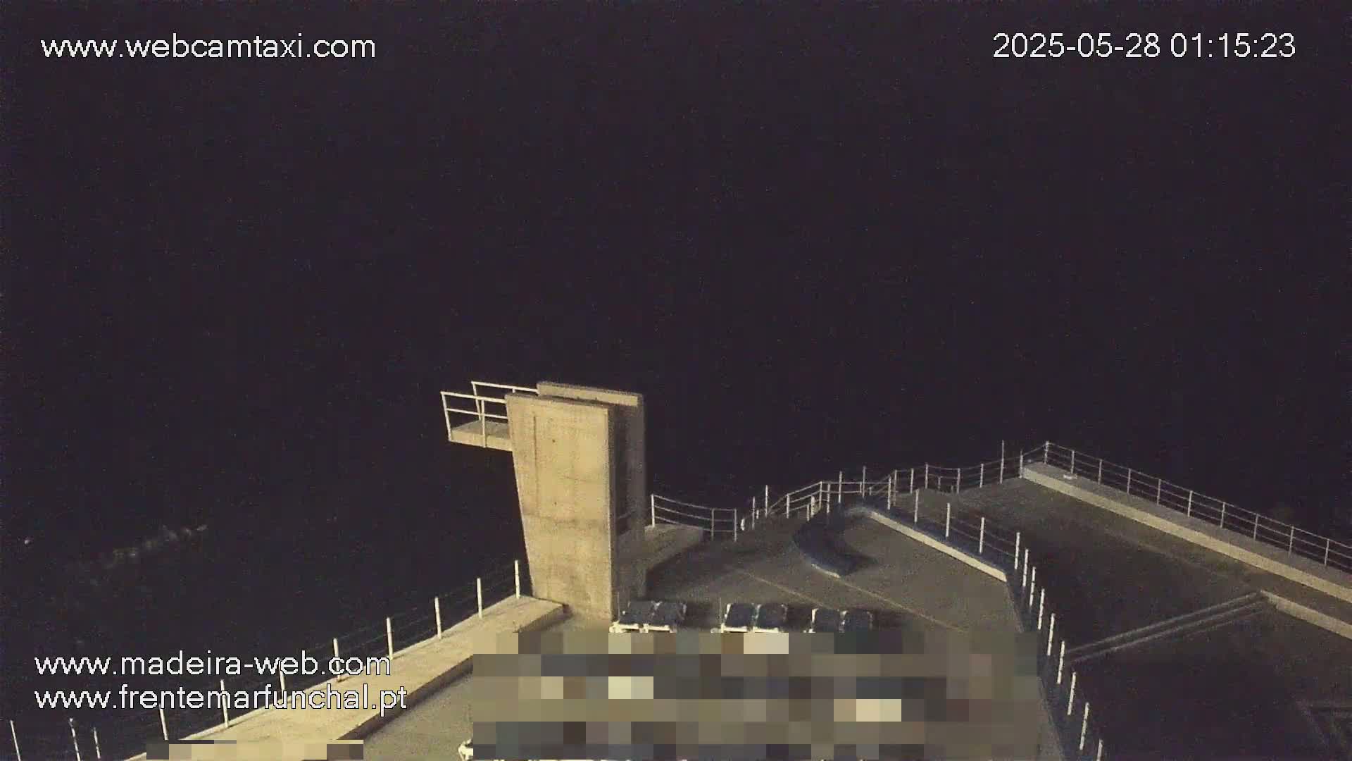 A nighttime view of a concrete diving platform overlooking dark water under a clear, dark sky.