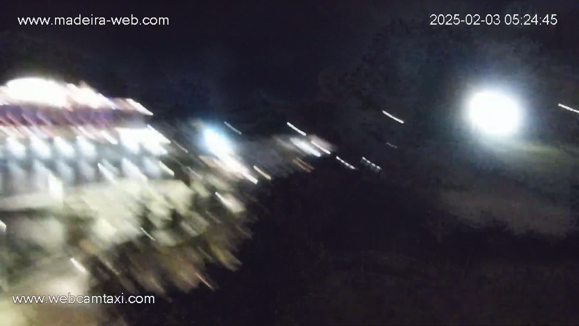 A blurry nighttime image shows a brightly lit amusement park ride in motion under a bright moon.
