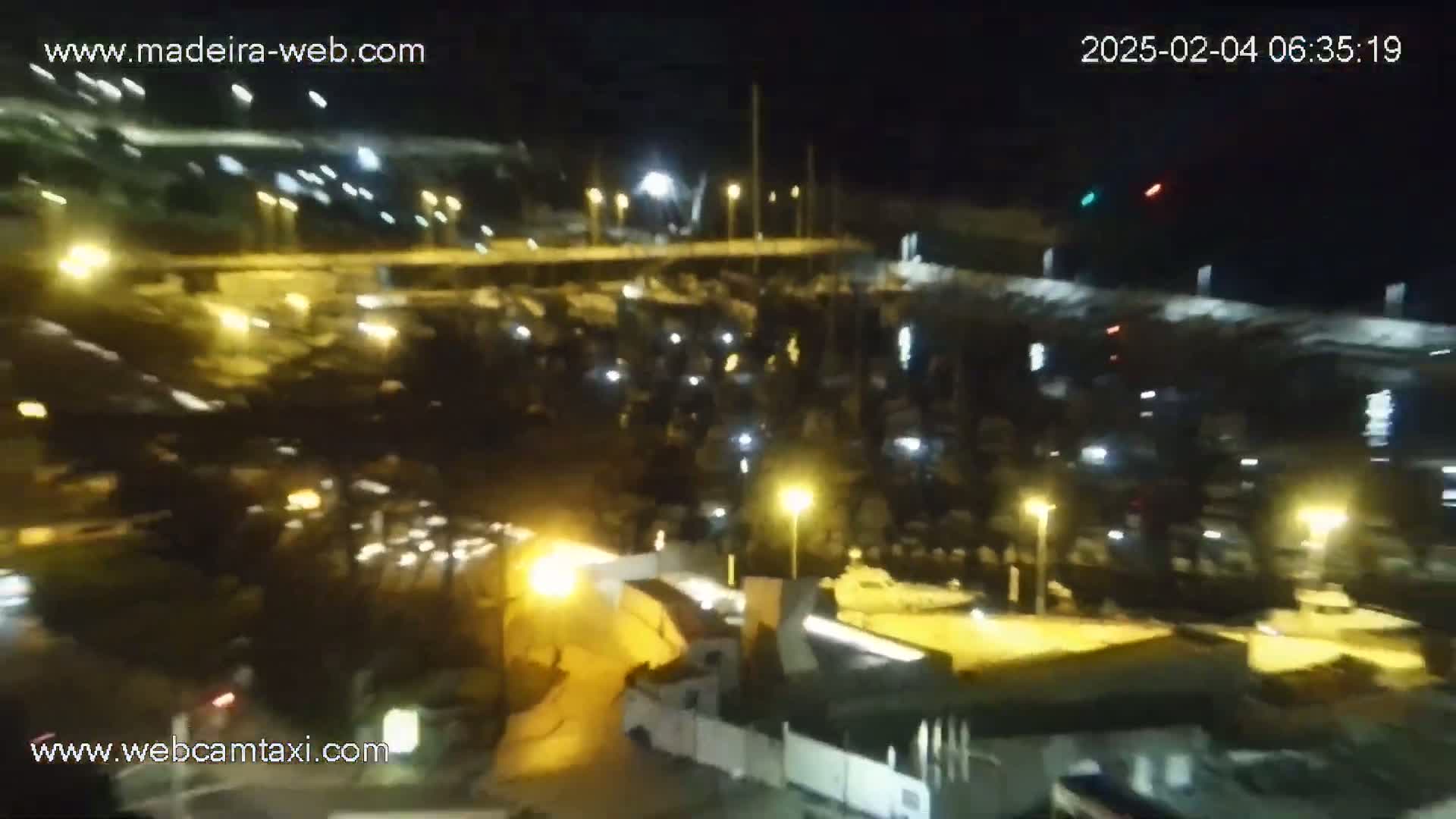 A nighttime aerial view of a marina filled with boats illuminated by artificial lights.
