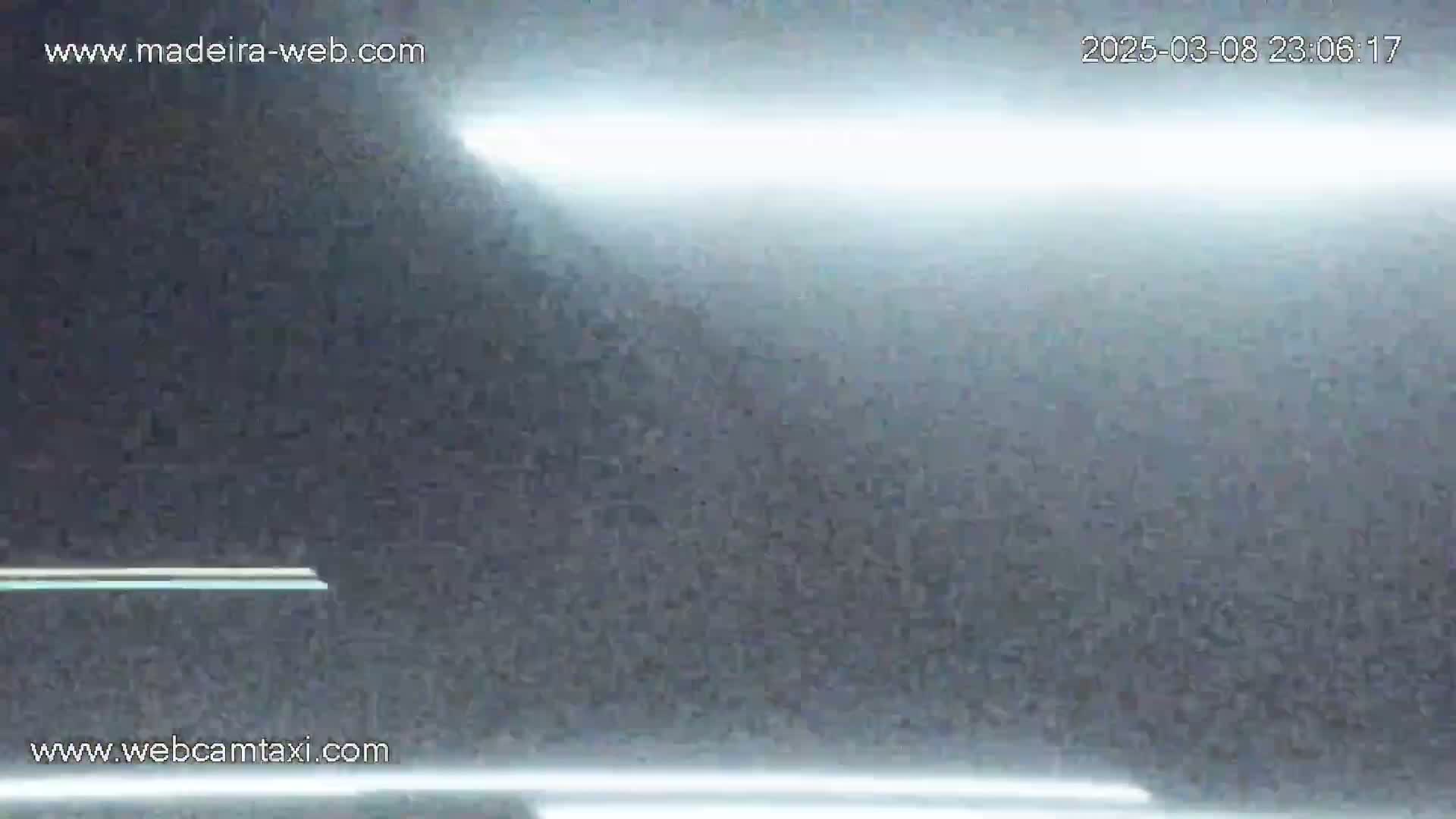 A mostly dark, blurry image shows bright horizontal lights at the top and bottom, with a hazy or foggy atmosphere.