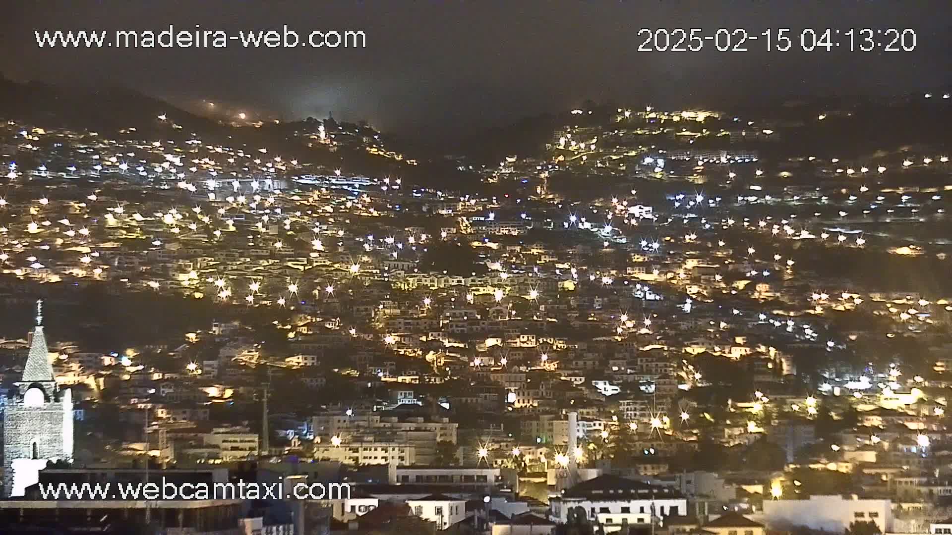 A densely populated hillside town is brightly lit at night.