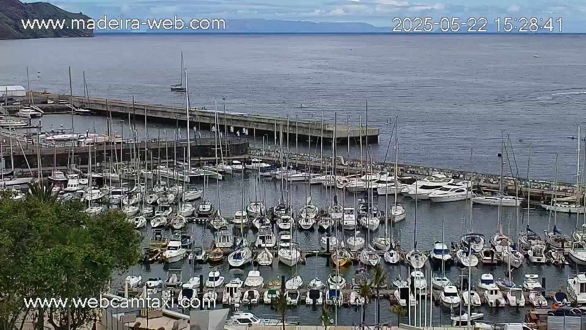 A harbor filled with numerous sailboats and motorboats under a partly cloudy sky.