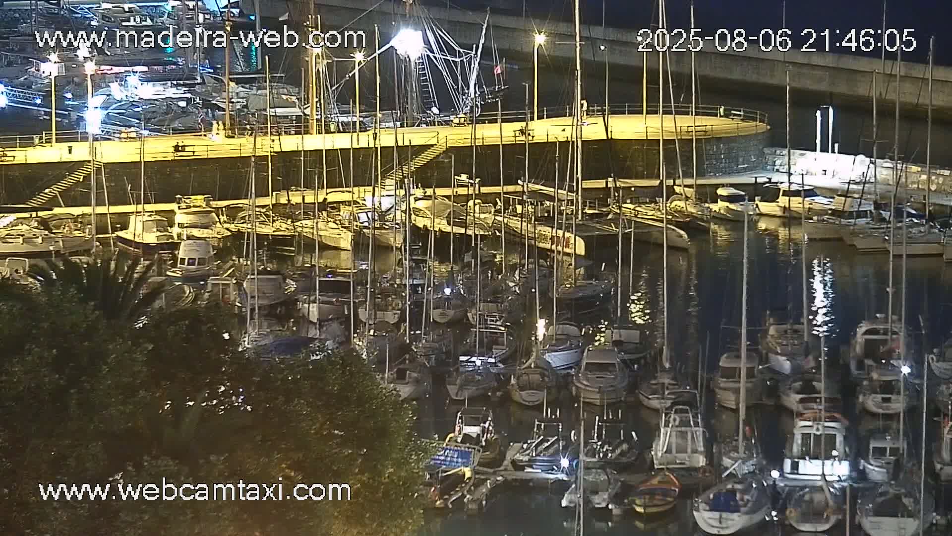 A nighttime view of a marina filled with numerous boats and yachts docked under calm water.