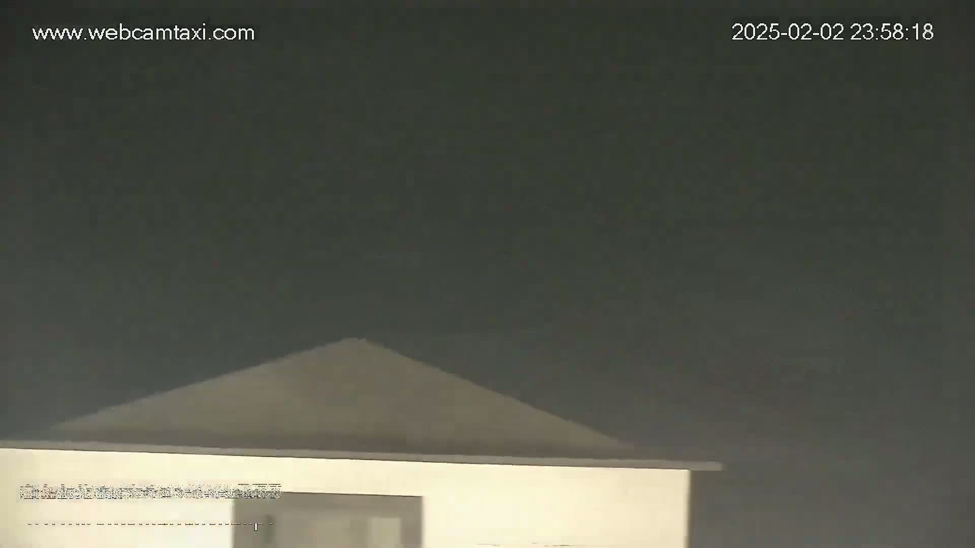 A dark, overcast night sky is visible above the gabled roof of a light-colored building.