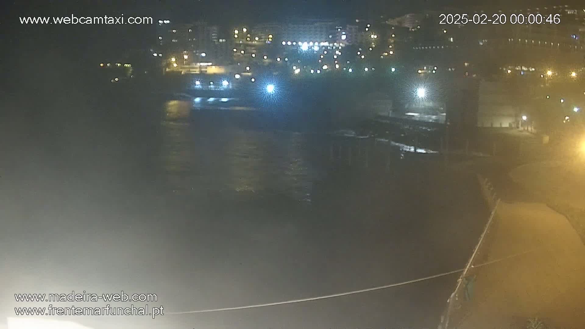 A nighttime, dark view of a body of water with city lights and buildings in the background.