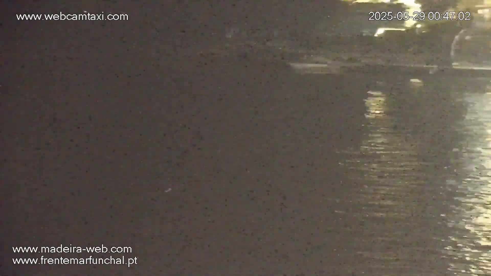 A dark, nighttime image shows a body of water with subtle reflections on its surface.