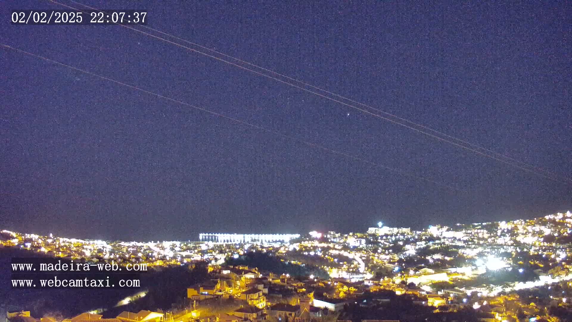 A nighttime view of a city illuminated by lights under a clear, dark sky.