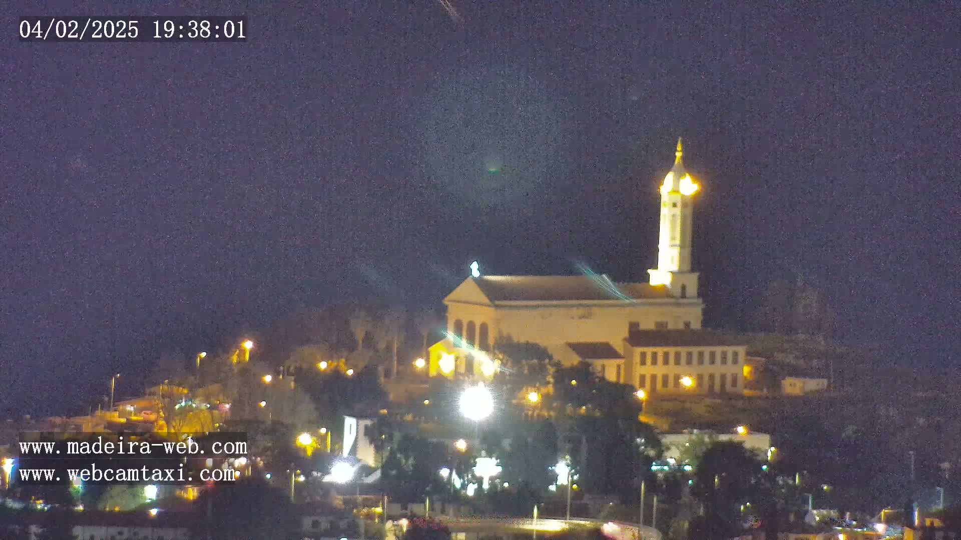 A brightly lit church with a tall tower is visible at night, under a dark, clear sky.