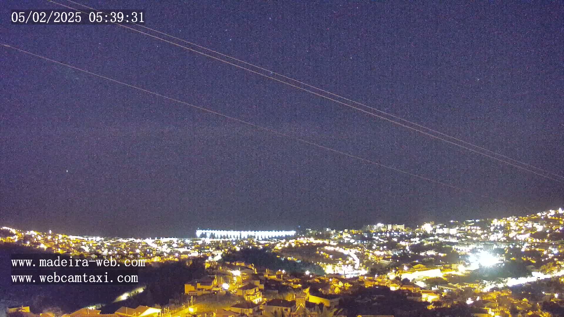 A nighttime view of a city illuminated by lights under a clear, starry sky.