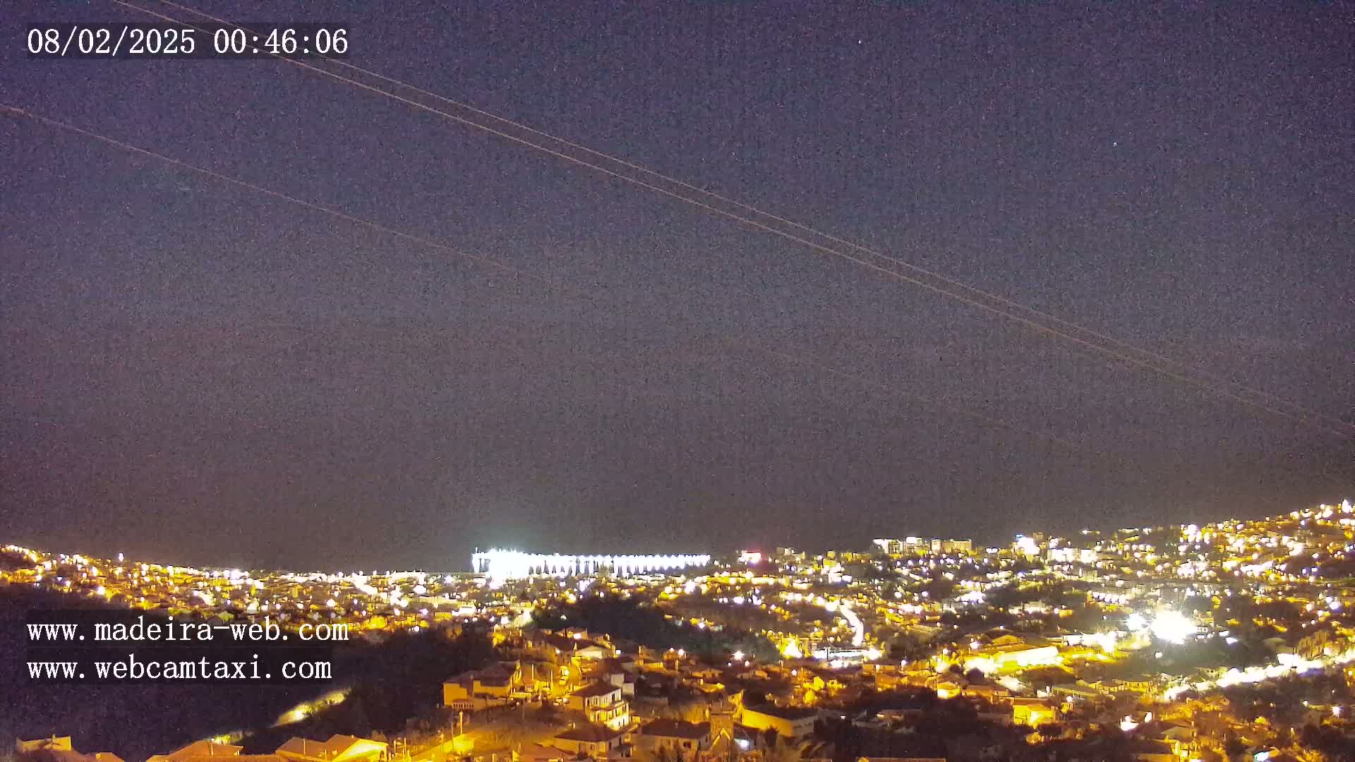 A nighttime long shot of a city illuminated by lights under a clear, dark sky.