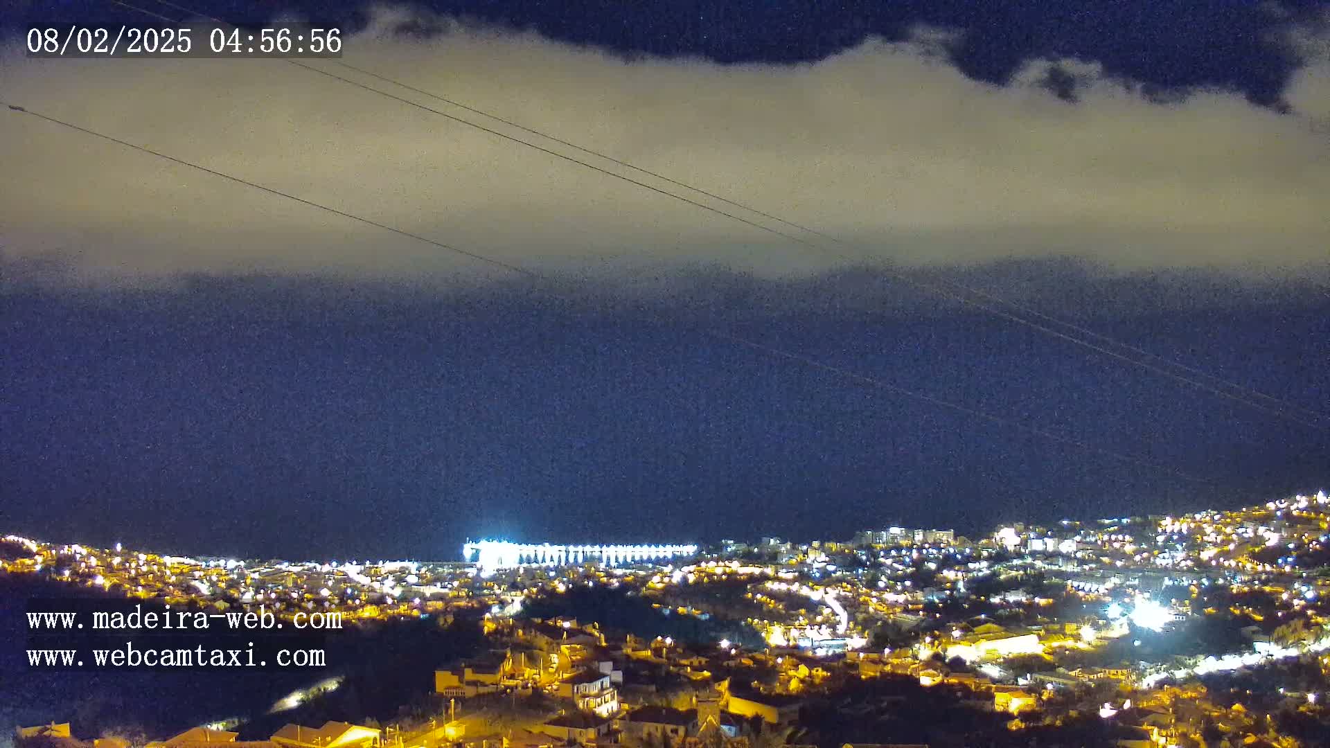A nighttime view of a city illuminated by lights under a cloudy sky.