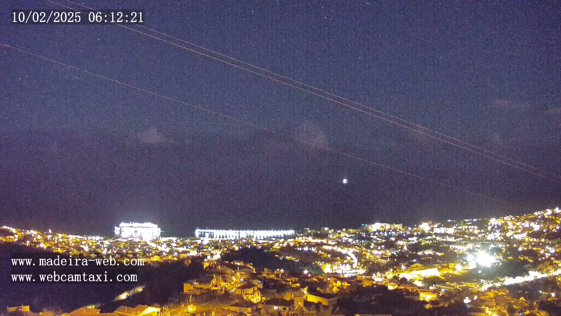 A nighttime view of a city illuminated with lights under a clear, starry sky.
