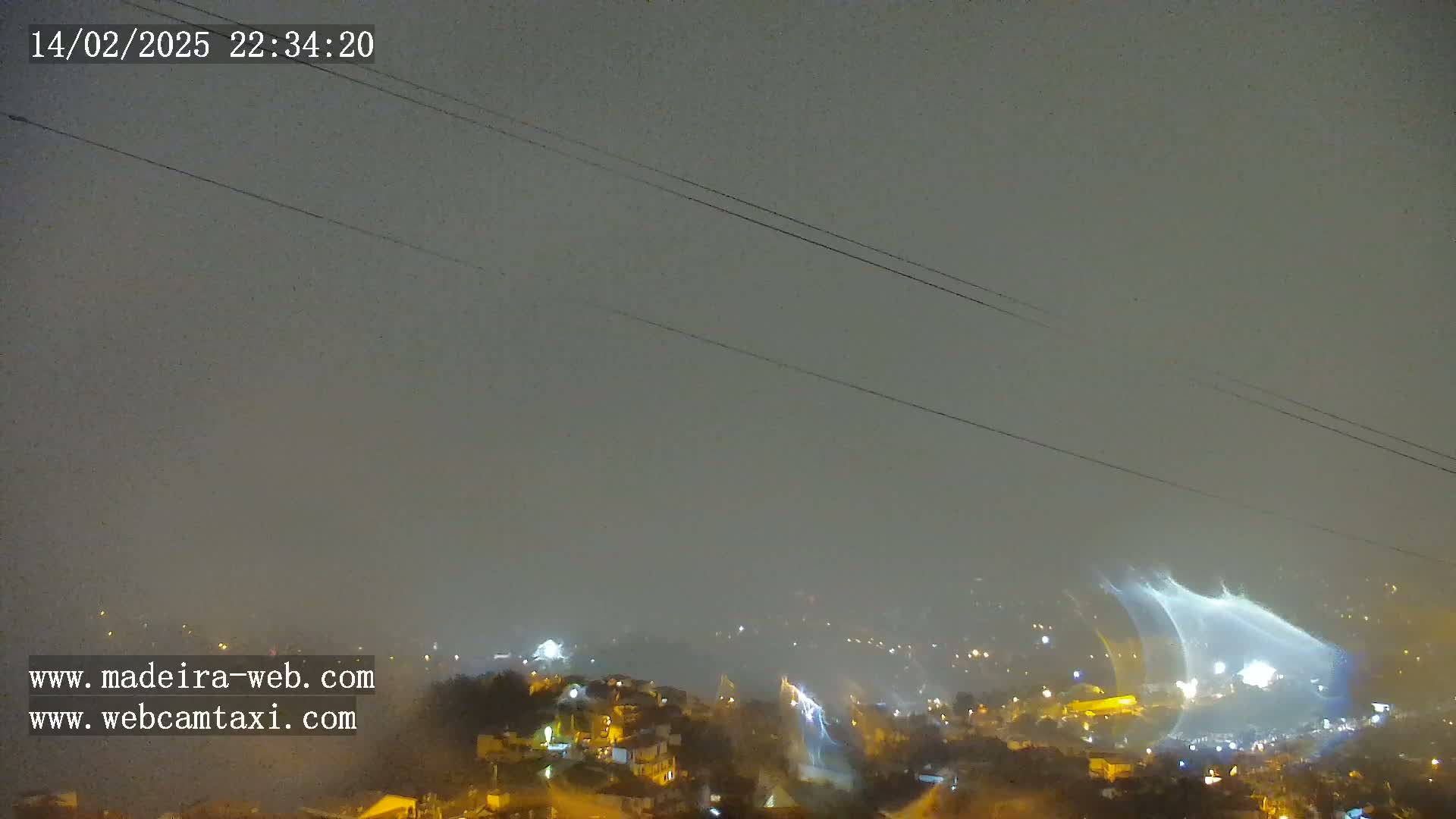 A nighttime view of a rain-soaked town with lightning illuminating the scene under a gray sky.