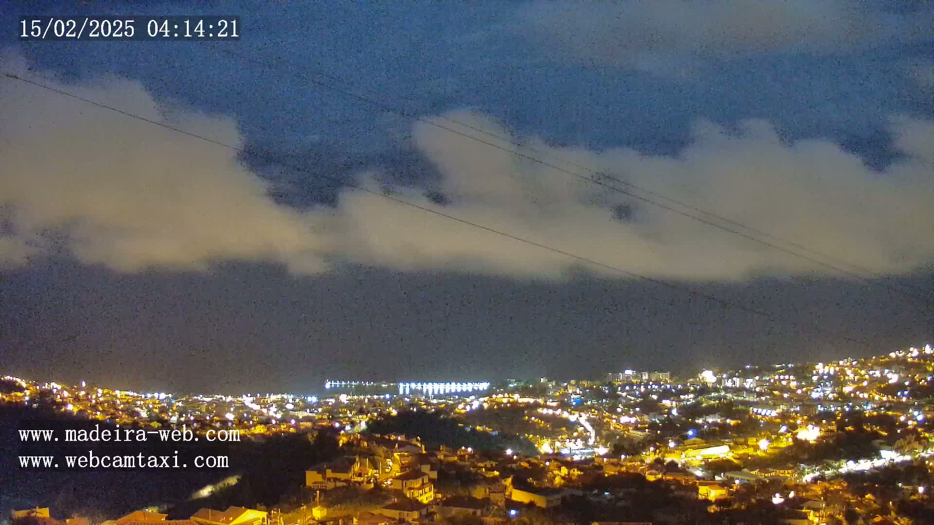 A nighttime view of a city illuminated by lights under a cloudy sky.