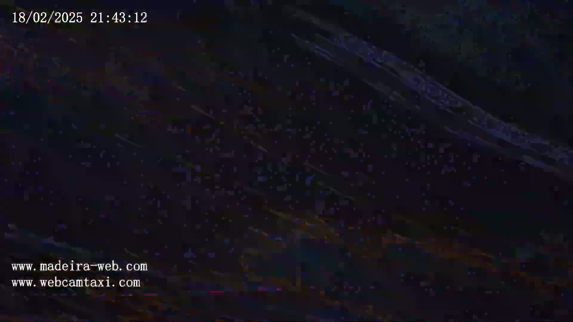 The image shows a dark, blurry scene with streaks of light suggesting a nighttime, possibly poor signal webcam feed.