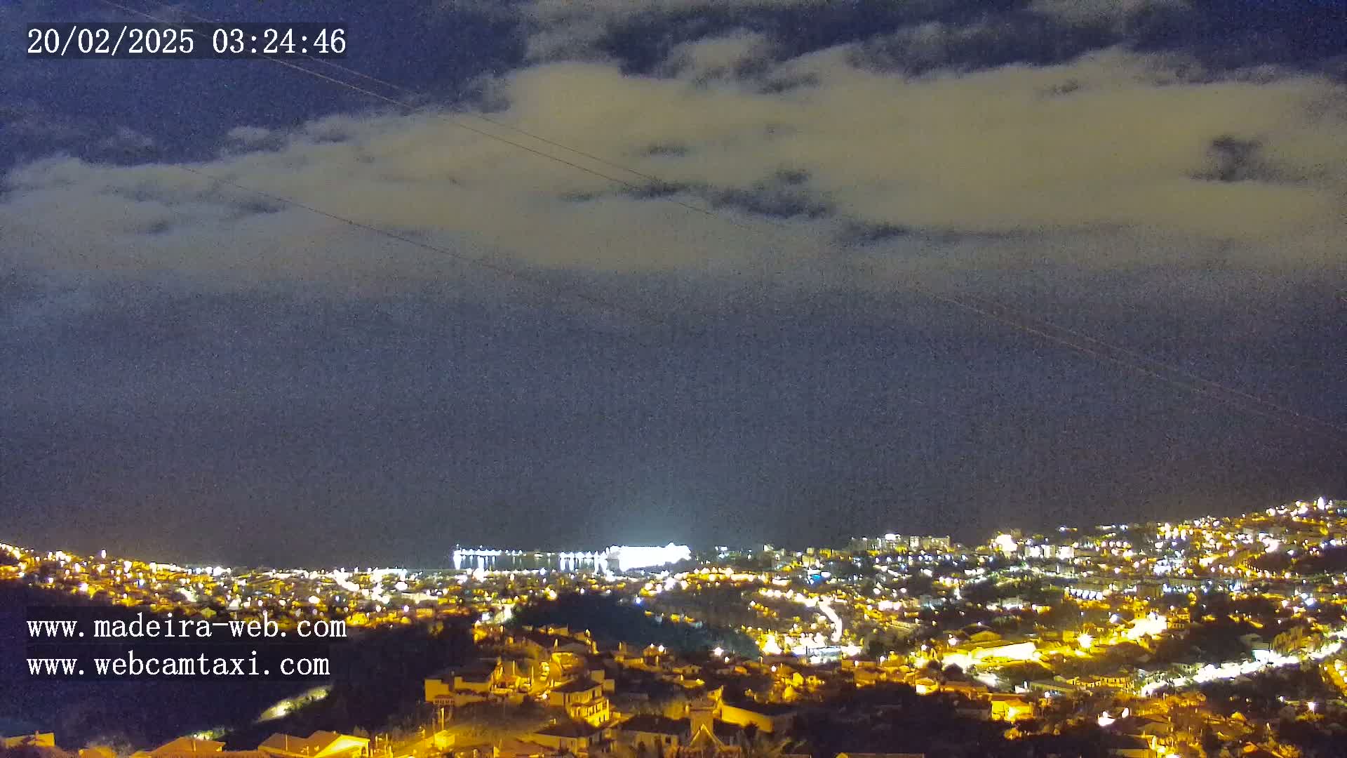 A nighttime view of a city illuminated by lights under a cloudy sky.