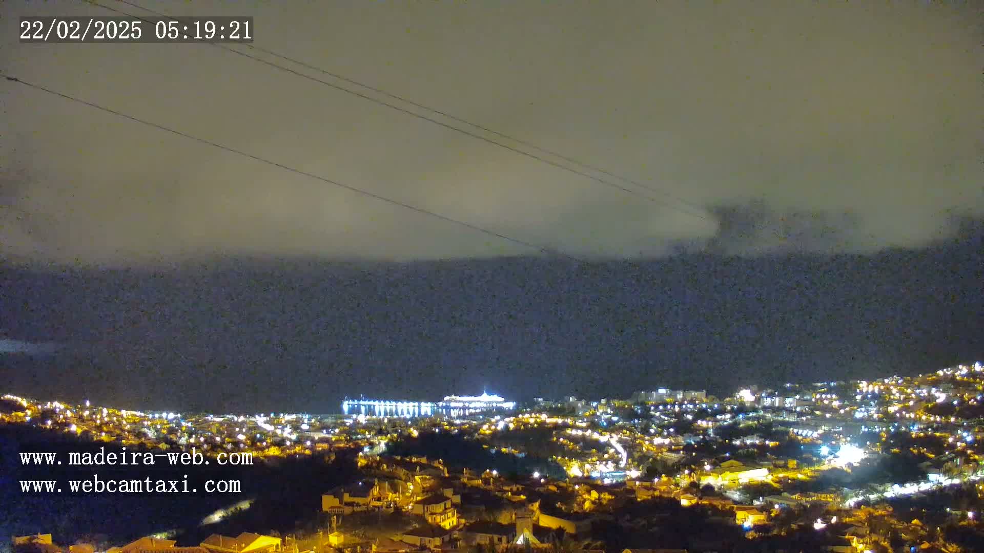 A nighttime view of a city illuminated by lights under a cloudy sky.