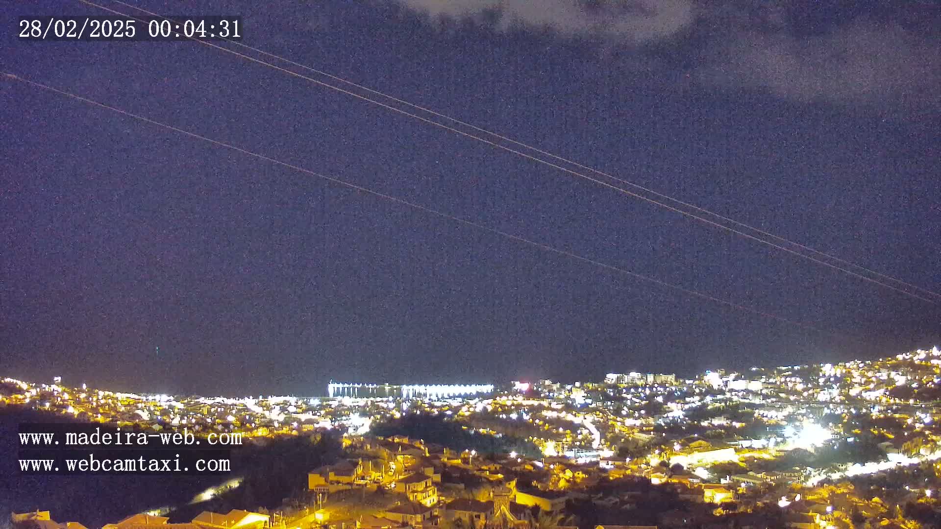 A nighttime view of a city illuminated by lights under a dark, mostly clear sky.