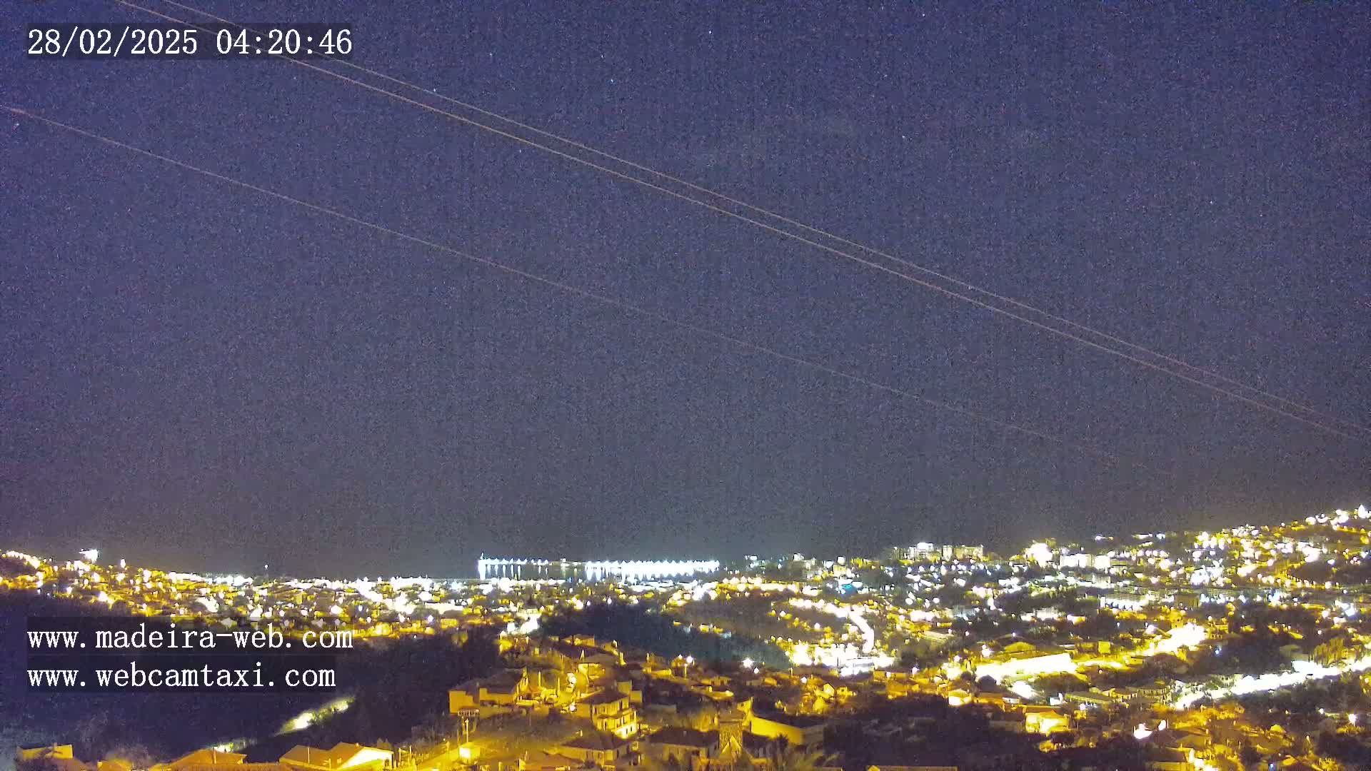 A nighttime view of a city illuminated by lights under a clear, starry sky.