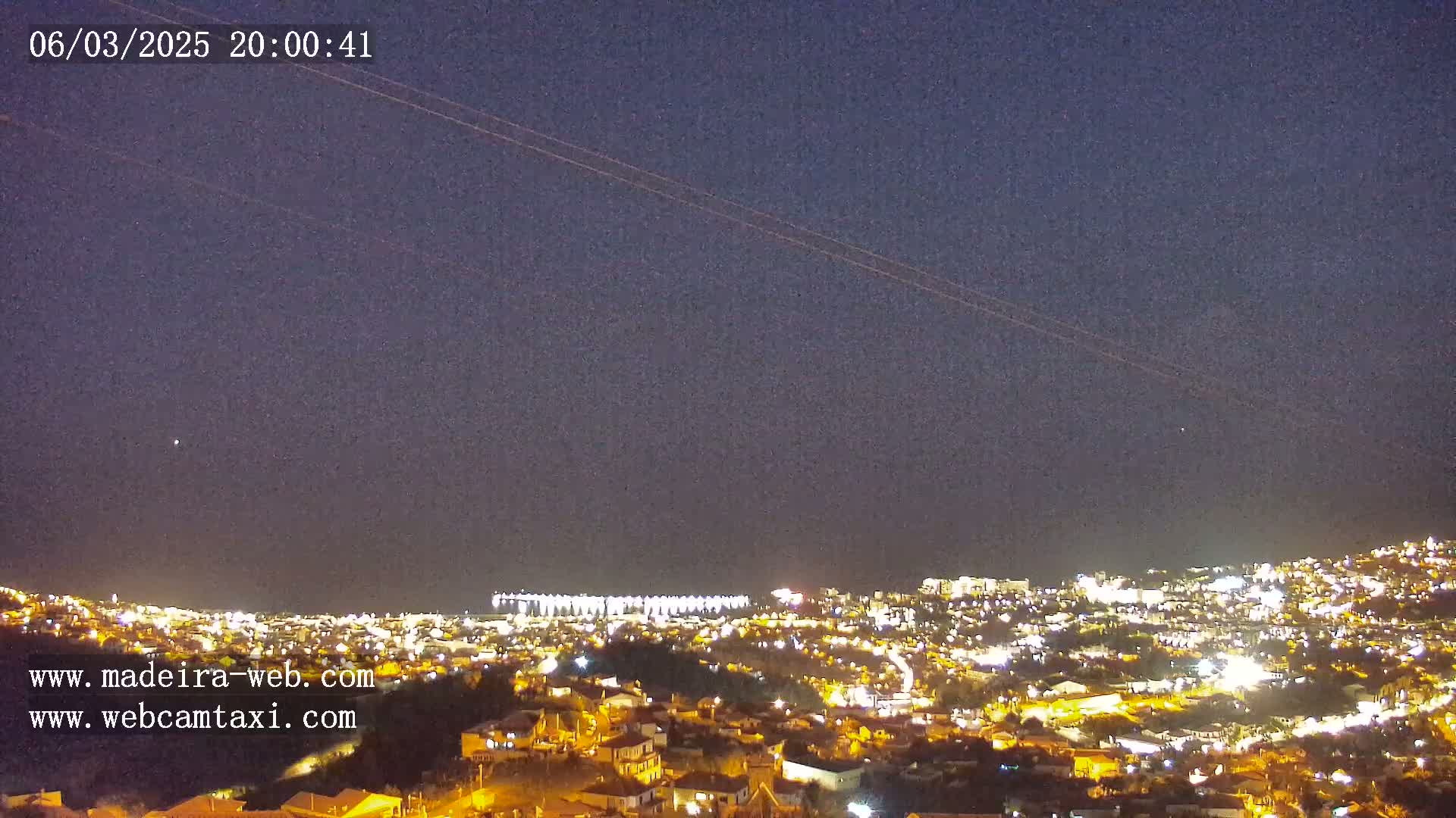 A nighttime view of a city illuminated by lights, under a clear, dark sky.