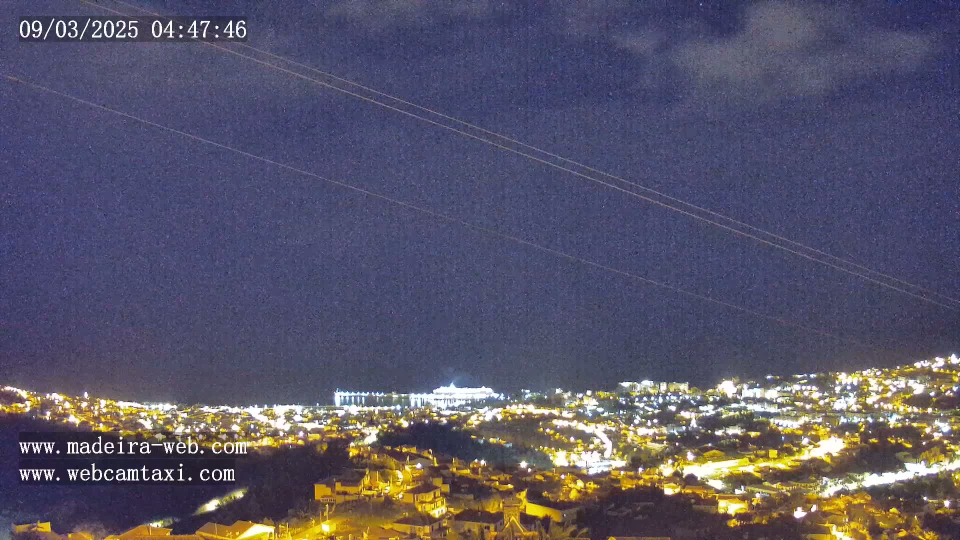 A nighttime view of a city illuminated by many lights under a dark, mostly clear sky.