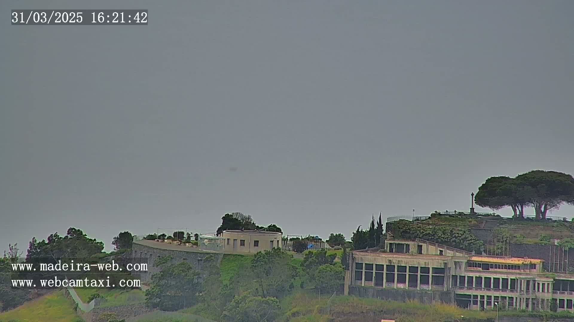 A distant view of a complex of buildings on a hill under an overcast sky.