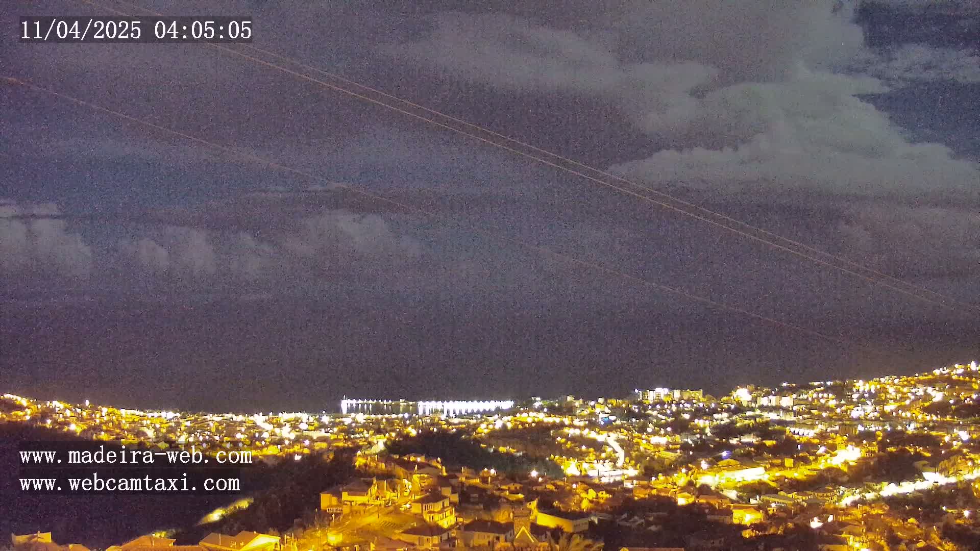 A nighttime view of a city illuminated by lights under a cloudy sky.