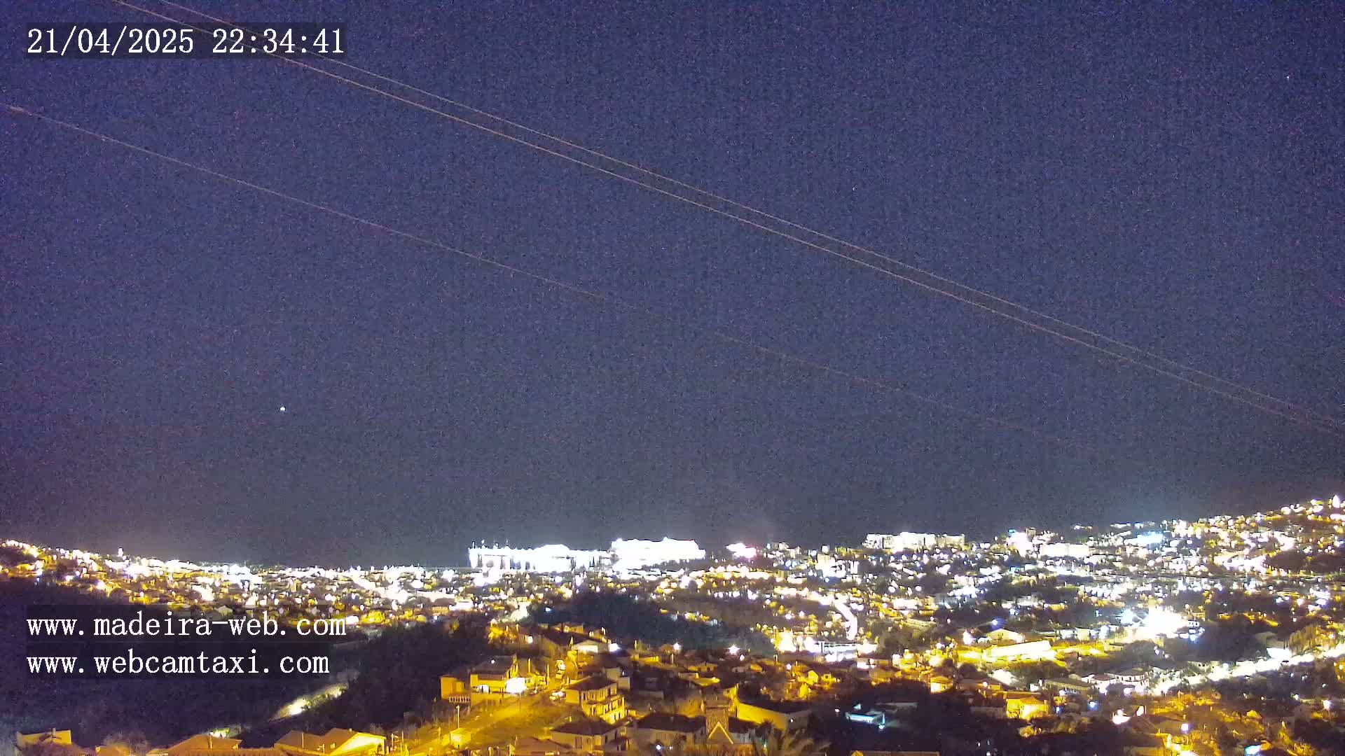A nighttime view of a city illuminated by lights under a clear, dark sky.
