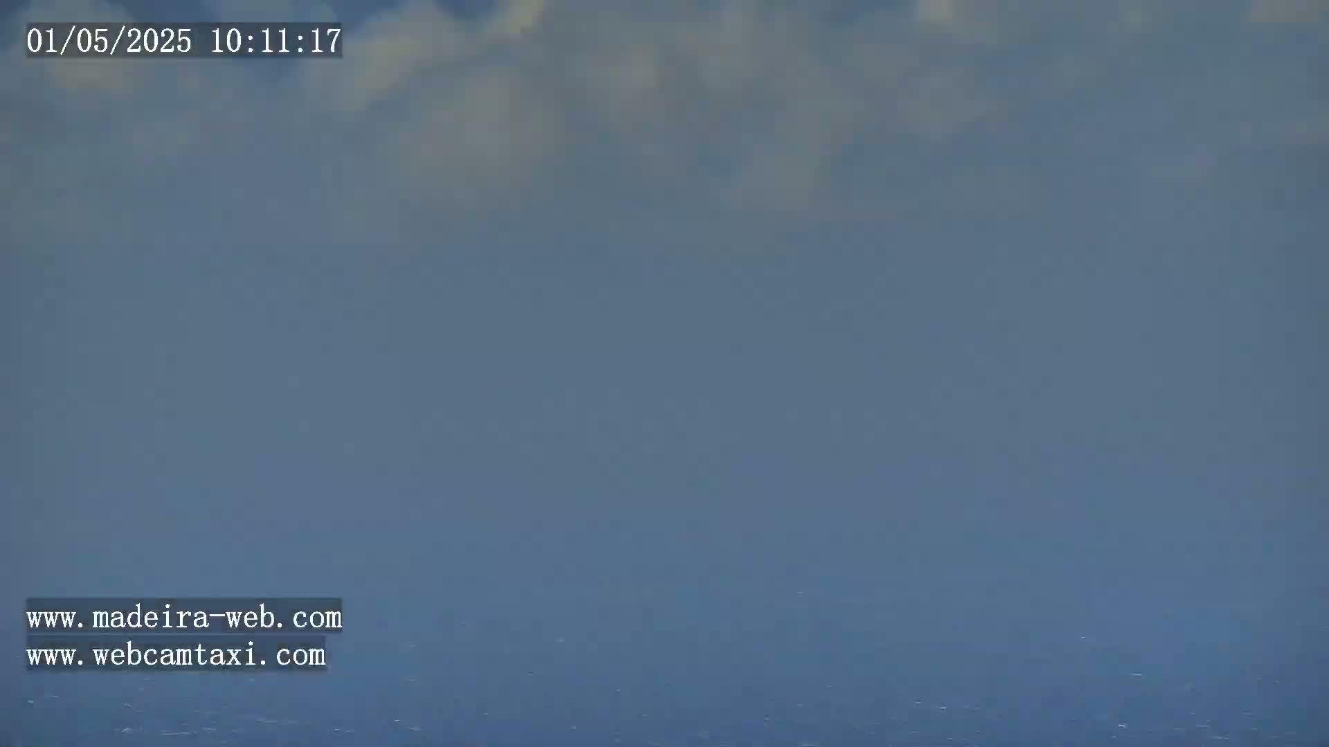 A hazy, overcast sky hangs over a calm ocean.