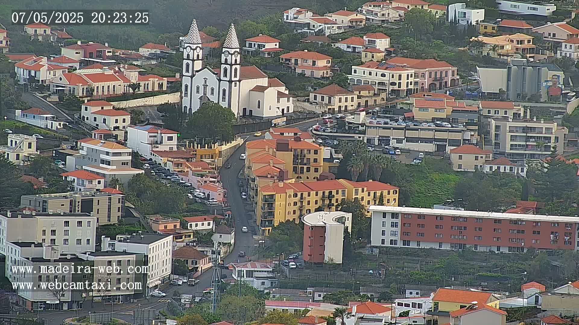 An aerial view of a town shows many buildings, including a large church, on a slightly overcast day.
