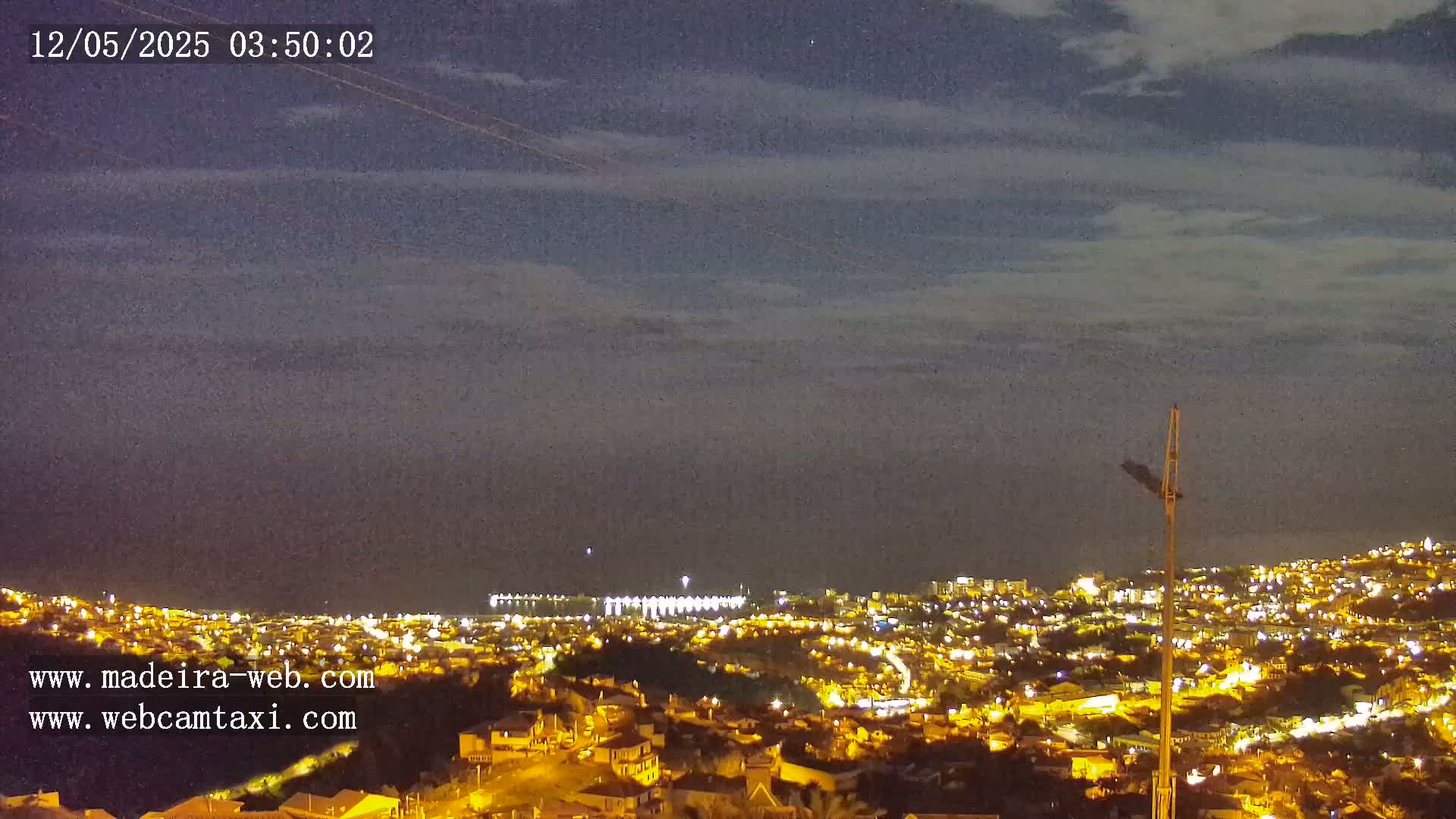 A nighttime view of a city illuminated with lights under a cloudy sky.