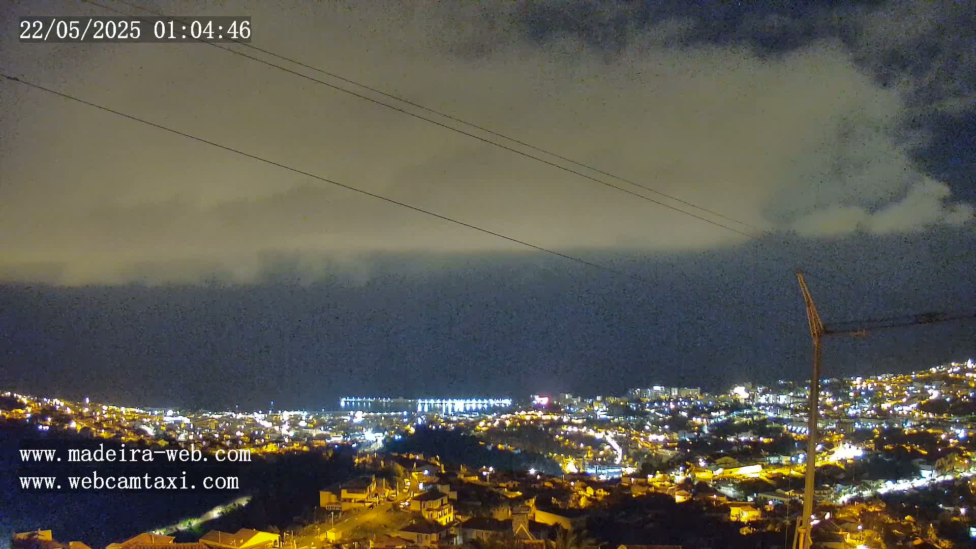 A nighttime view of a city illuminated with lights under a cloudy sky.