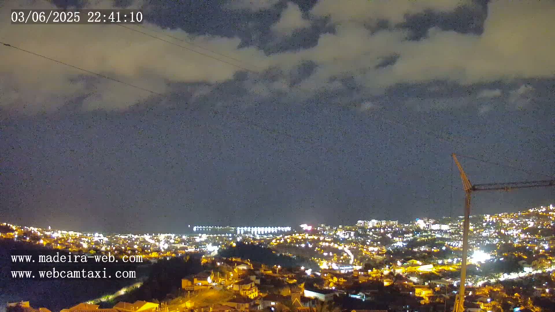 A nighttime view of a city illuminated with lights under a cloudy sky.