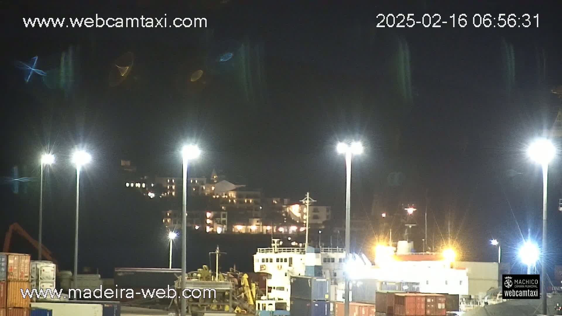 At night, brightly lit cargo ships and buildings are visible under a dark sky.