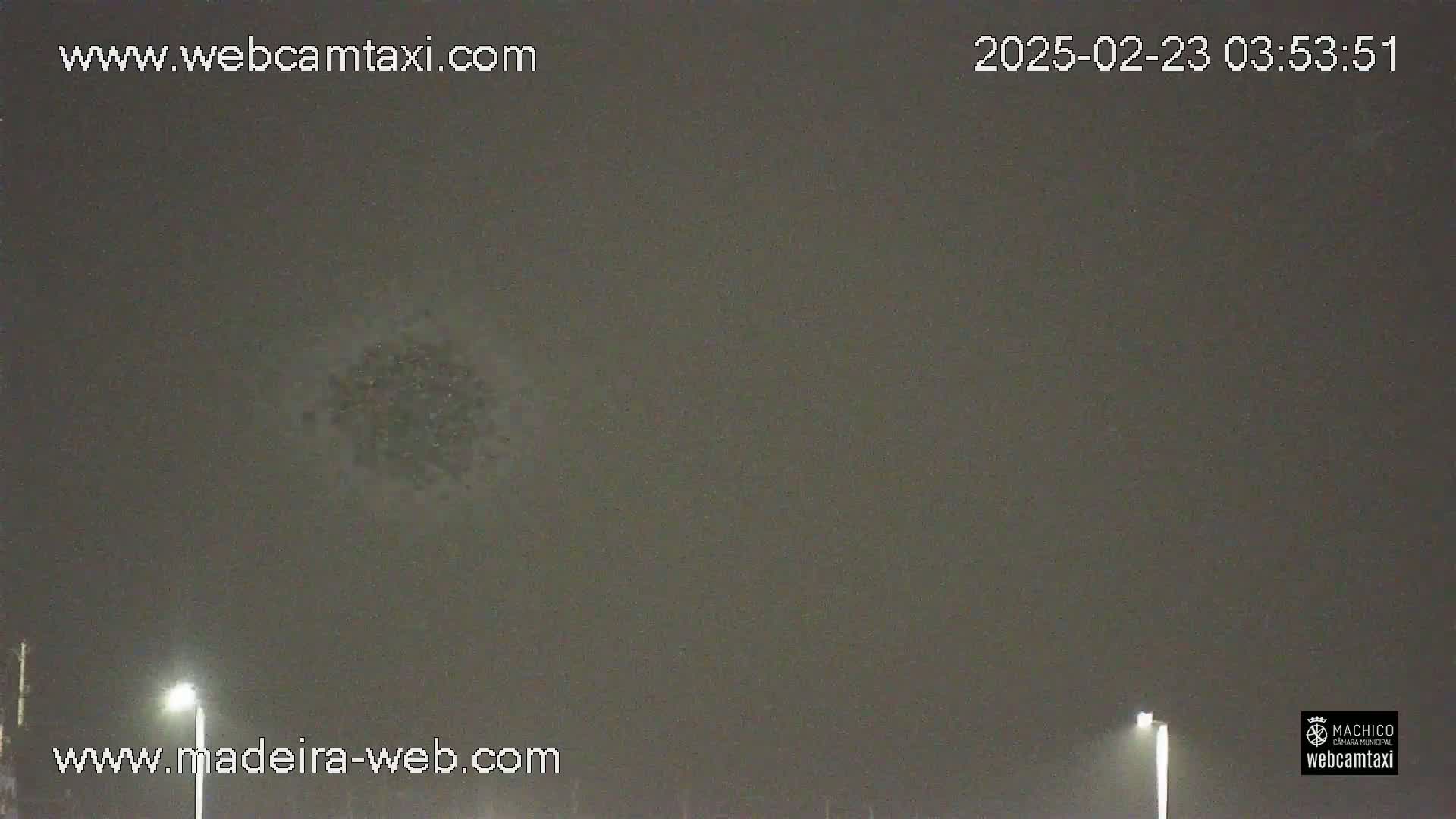 A dark, overcast night sky shows a small, indistinct cluster of lights in the center.